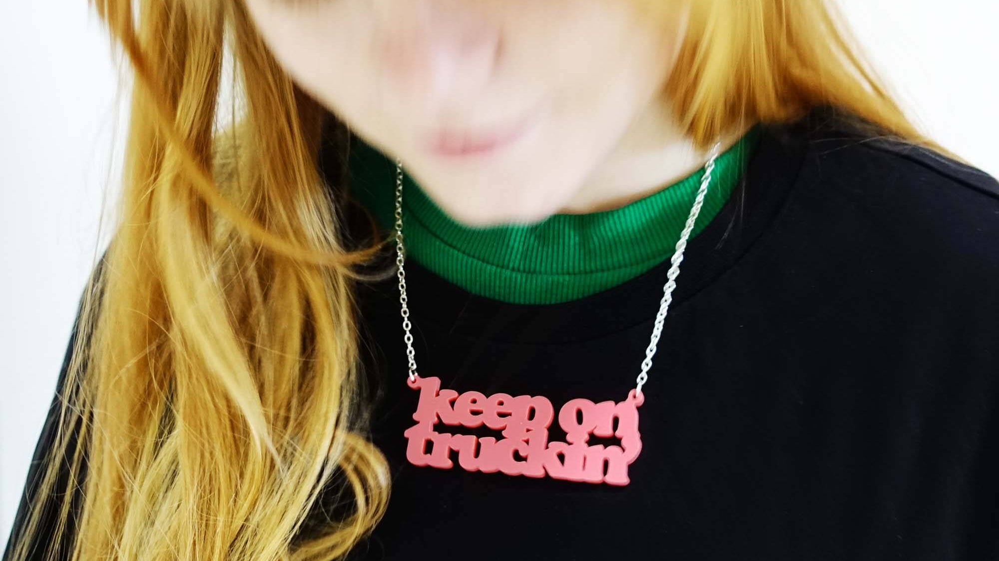 Eliza wears a Keep on Truckin' necklace in sunset pink, designed by Sarah Day for Wear and Resist.