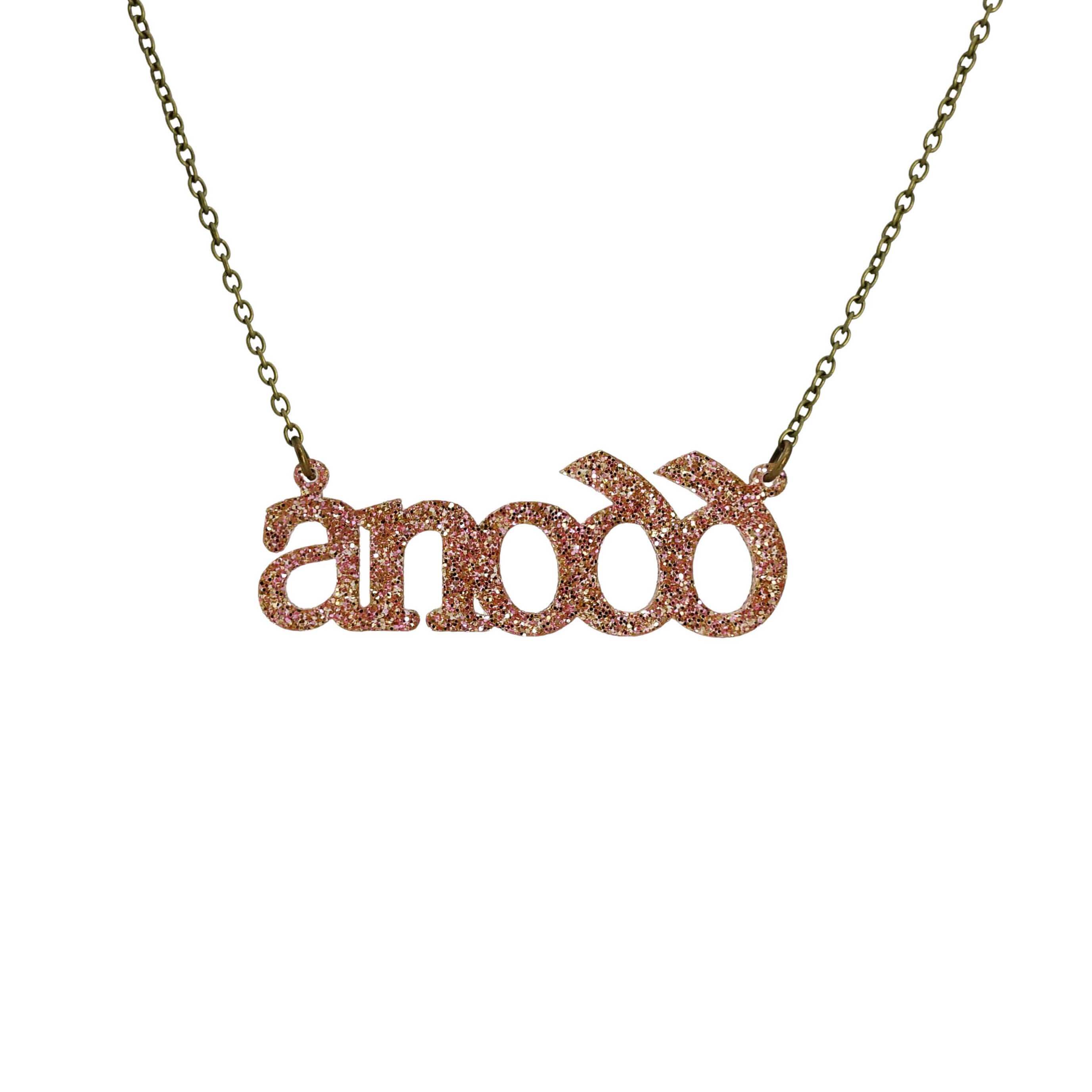 Anodd necklace for Welsh difficult women in pink fizz glitter shown hanging on an antique gold chain.