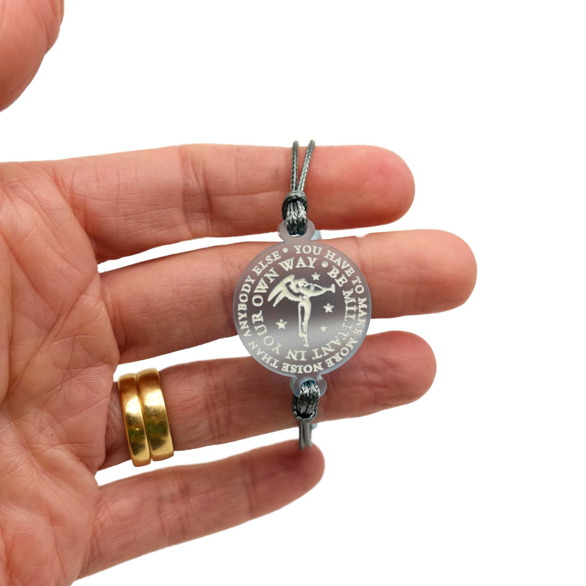 My hand holding up the bracelet with words etched in the glow in the dark pigment: 'You have to be militant in your own way. You have to make more noise than anybody else,' around Sylvia Pankhurst's Angel of Freedom.