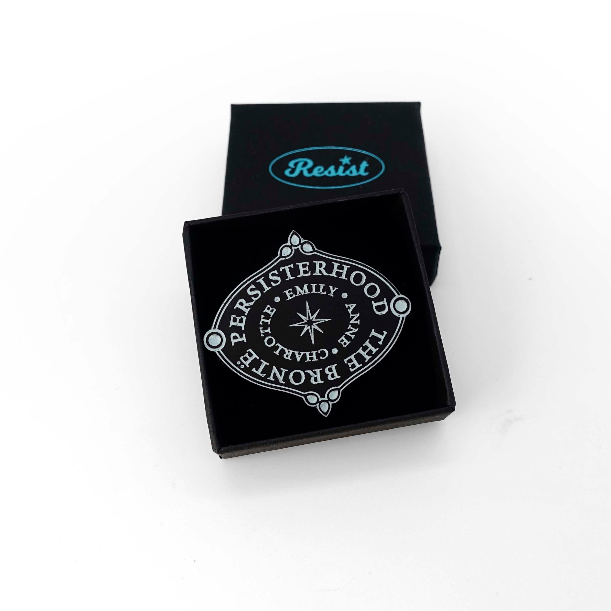 The Brontë Persisterhood brooch: Charlotte, Emily Anne, one of the greatest Persisterhoods in literature. The words are etched in glow-in-the-dark pigment. Shown in a Wear and Resist gift box.