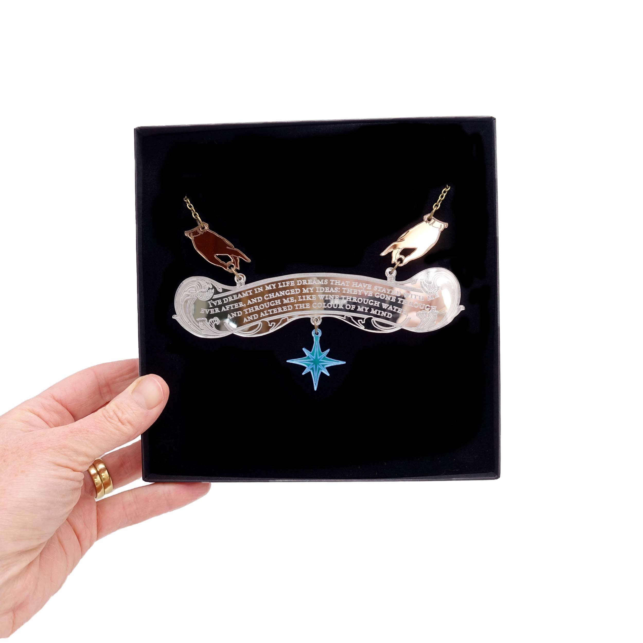 The Wuthering Heights Dreams necklace shown held up in a Wear and Resist gift box.