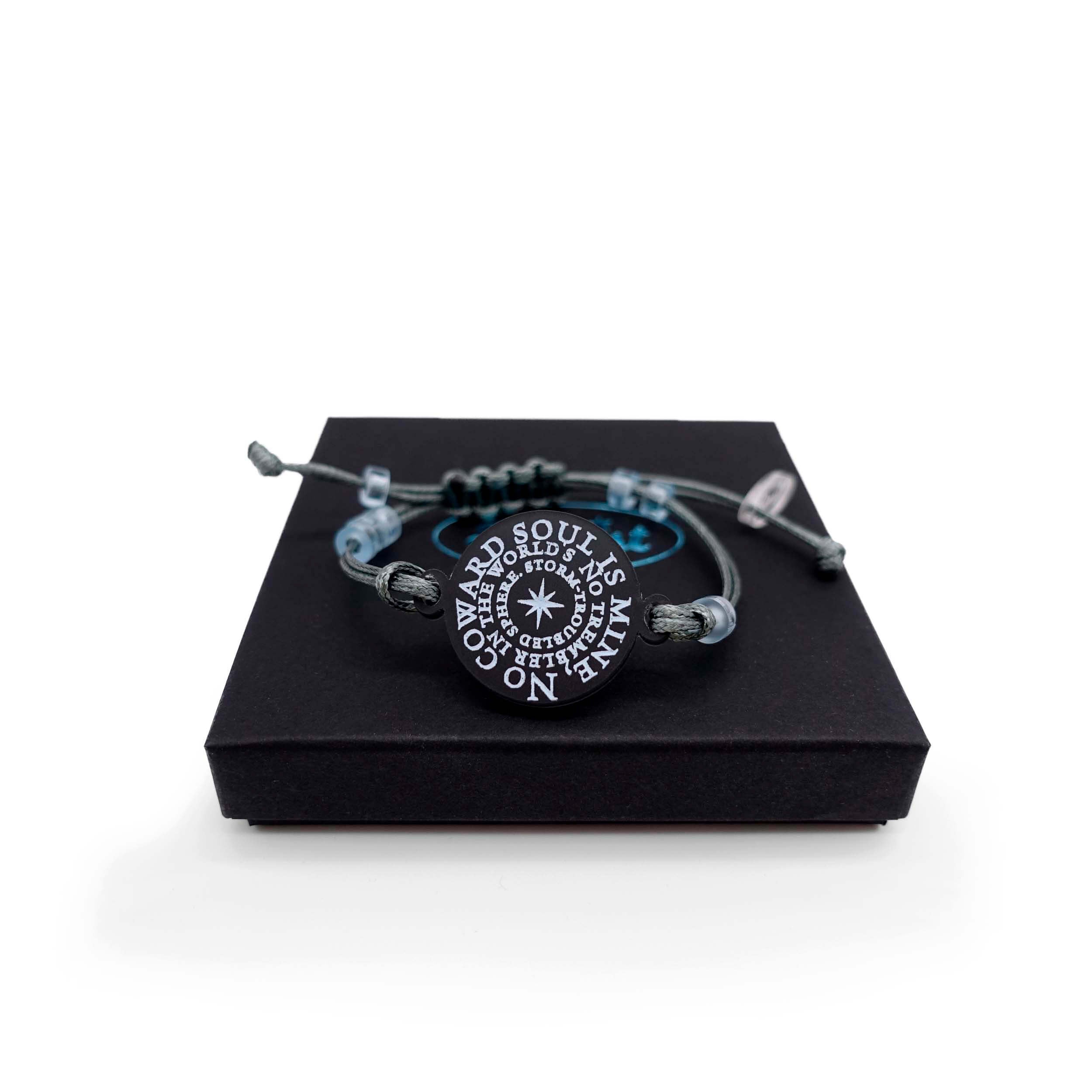 The No Coward Soul is Mine bracelet from the Brontë Collection. It is etched with the words from Emily Brontë's poem: No coward soul is mine. No trembler in the world's storm-troubled sphere in glow-in-the-dark pigment. Each one is hand tied by Sarah Day for Wear and Resist.