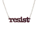 Cassis Resist necklace in typewriter font hanging on a silver chain against a white background.