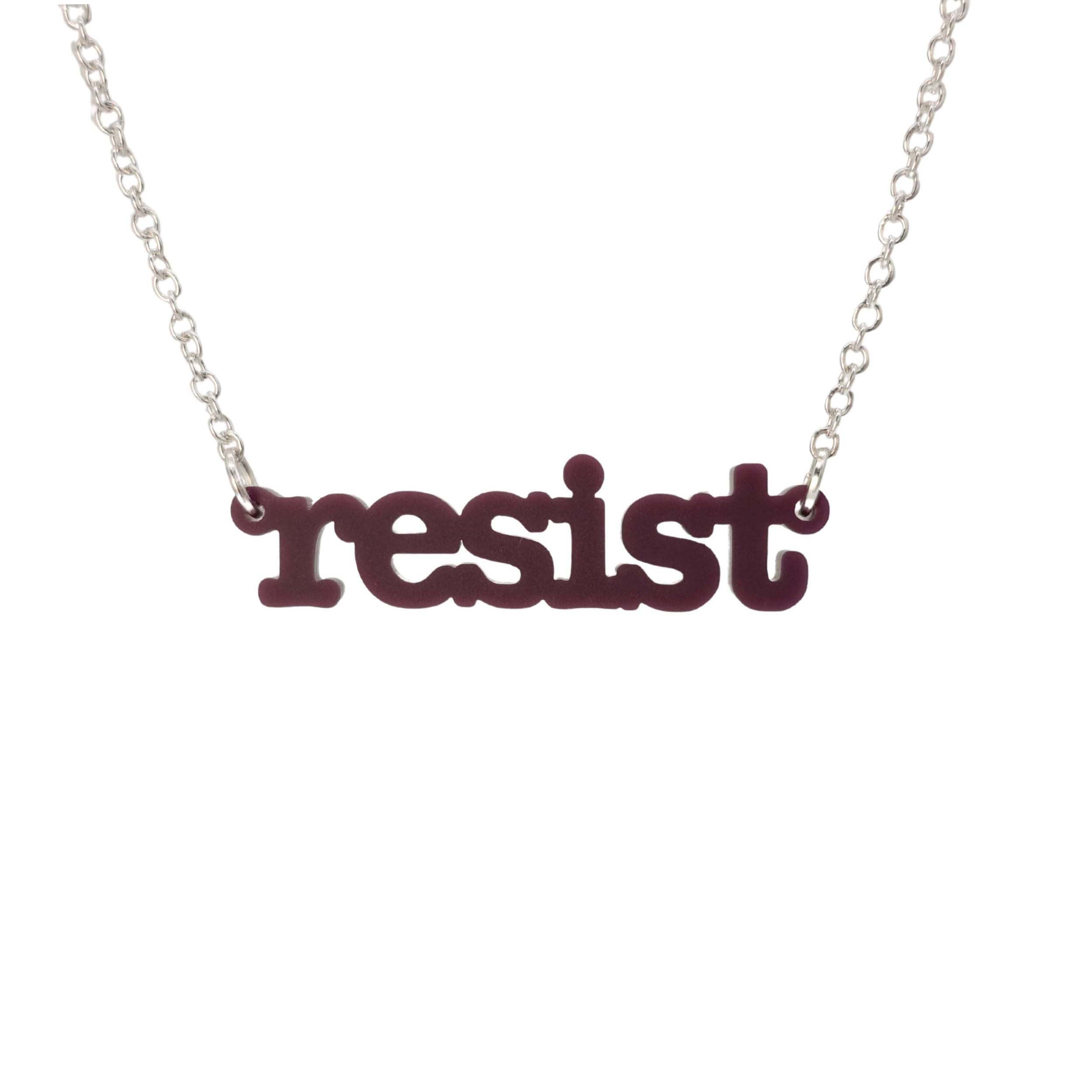 Cassis Resist necklace in typewriter font hanging on a silver chain against a white background.