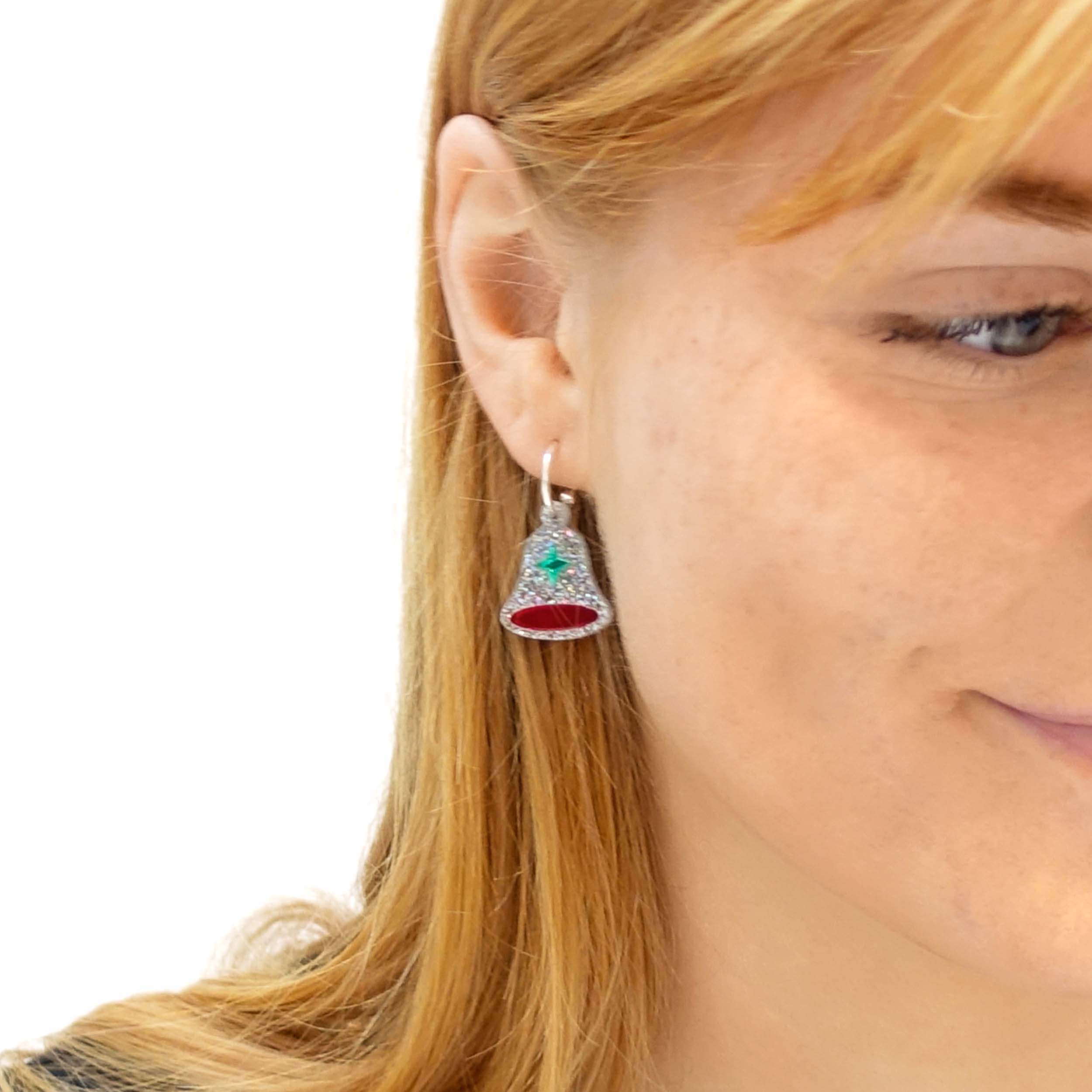A close up of Eliza wearing silver glitter bell hoop earrings.