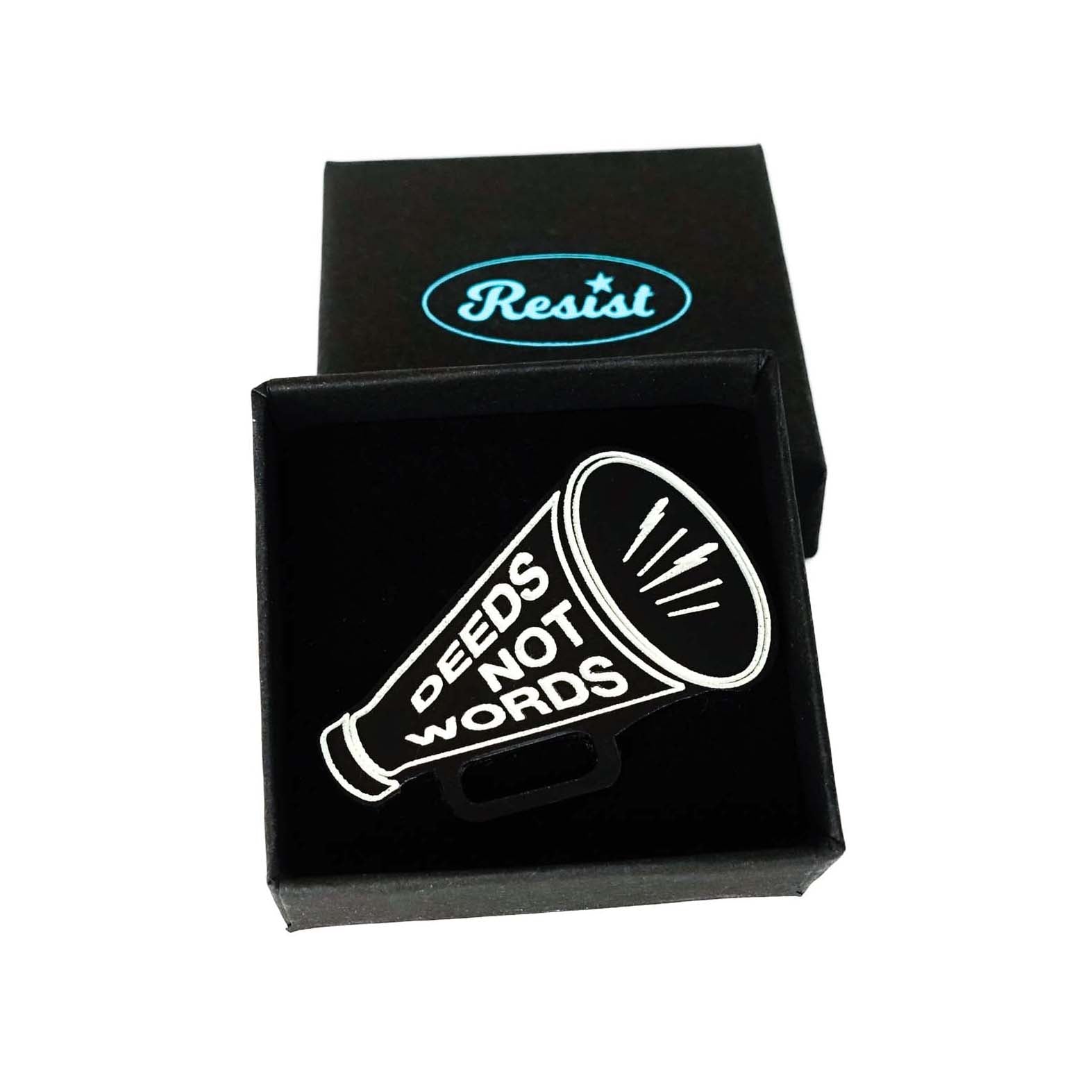 A small megaphone brooched etched with 'Deeds not words' shown in a little Wear and Resist gift box. This brooch glows in the dark.