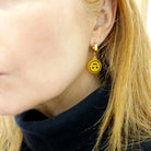 Sarah Day wears Upside-down smiley face earrings on gold huggie hoops.