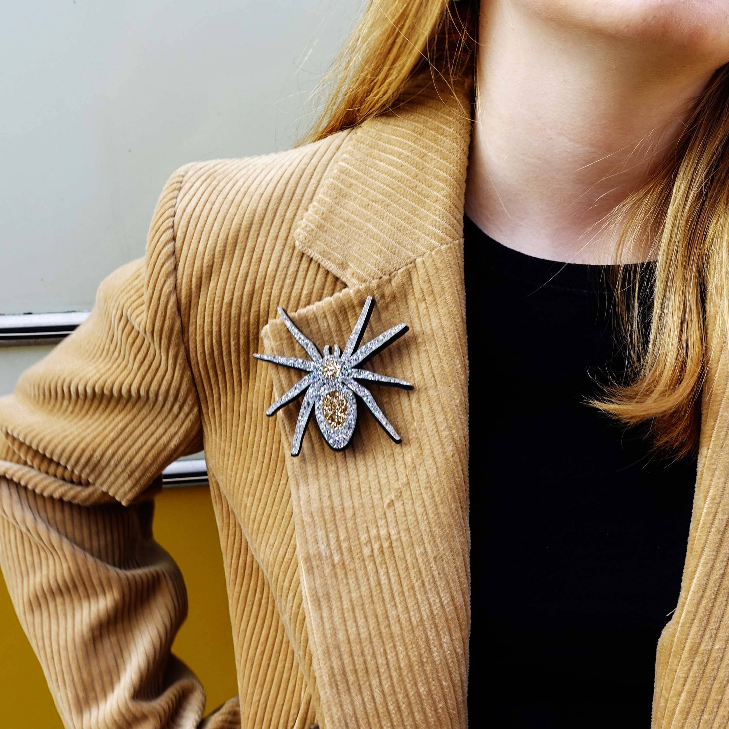 Eliza wears the All Hail Lady Hail Spider brooch on a tan corduroy jacket.