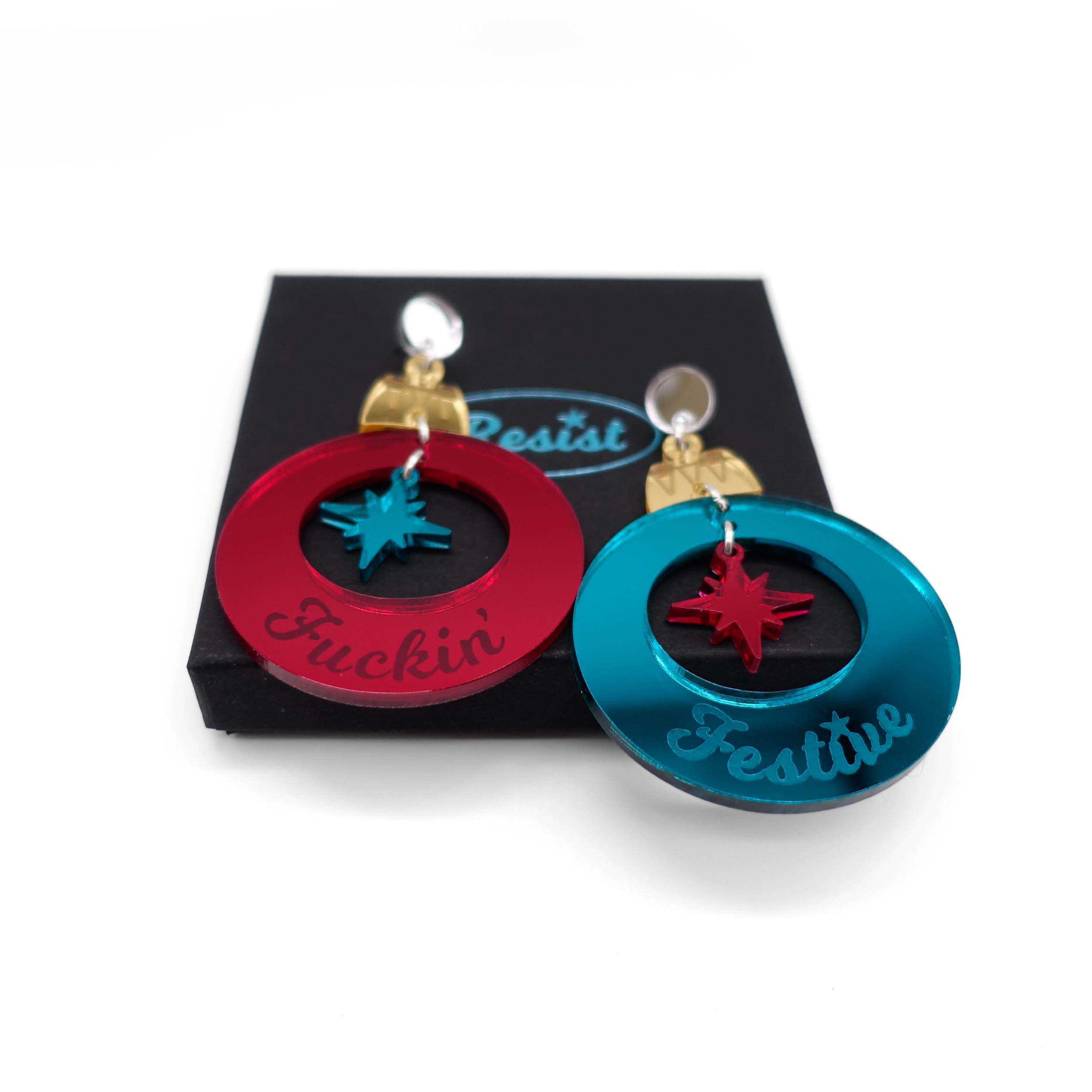 F*ckin Festive Christmas bauble earrings in ruby and teal mirror, shown on a Wear and Resist gift box. Happy Sweary Christmas!