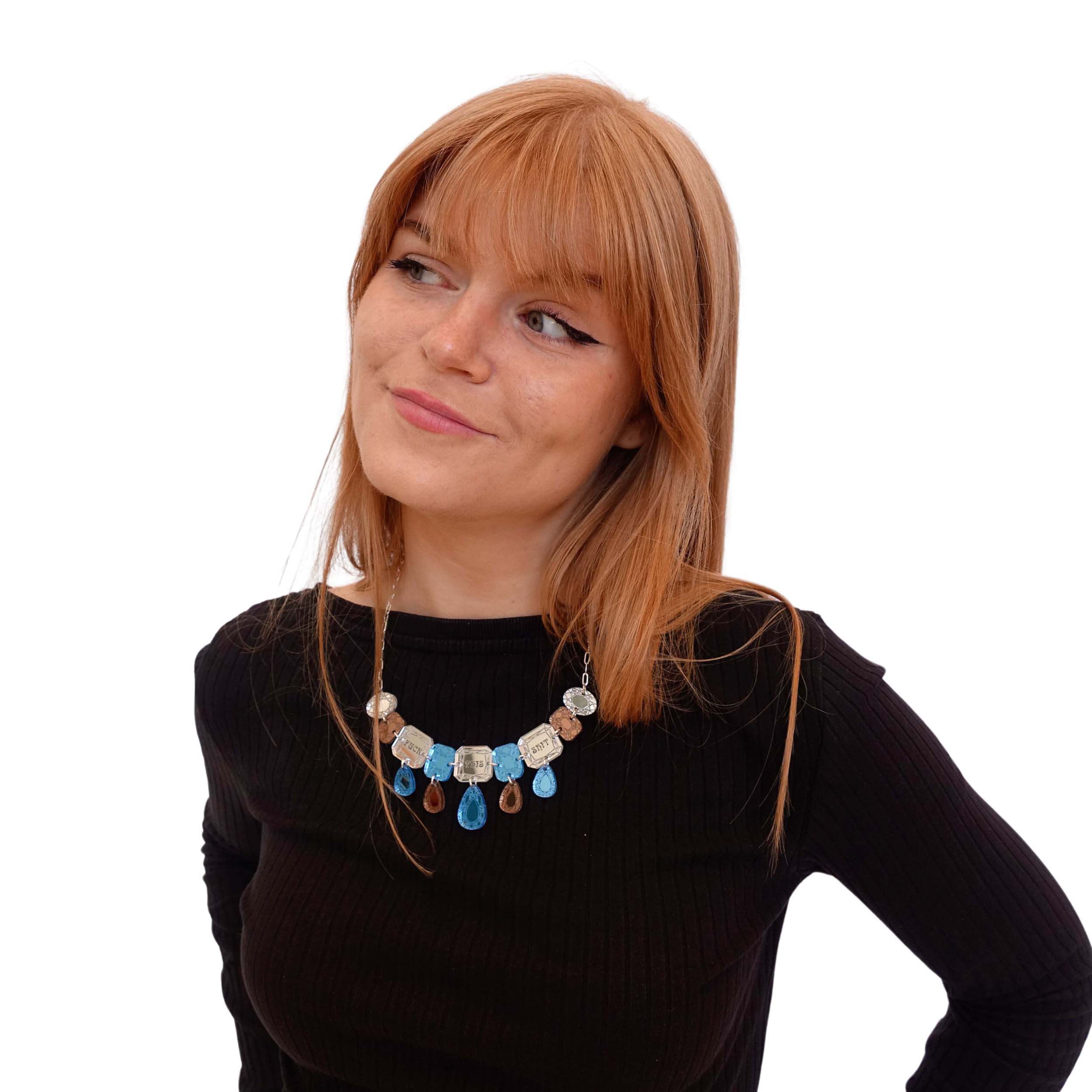 Eliza wears a blue silver and bronze F*ck this Sh*t jewel necklace.