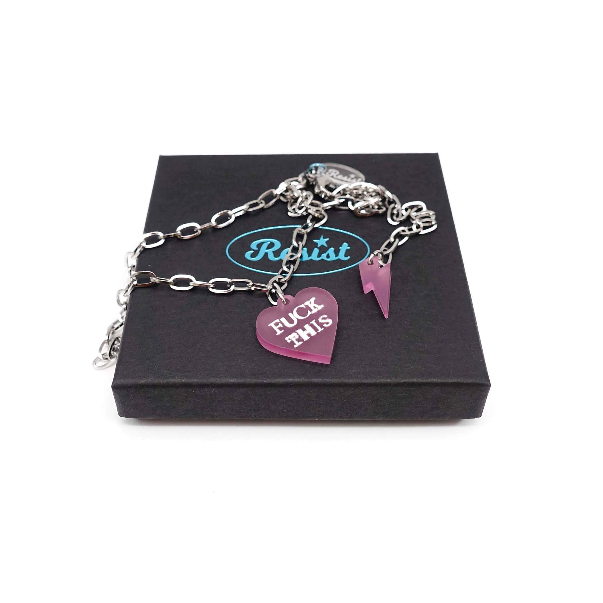 F*ck This punk necklace in pale pink frost with matching lightning bolt on a stainless steel chain, shown on a Wear and Resist gift box.