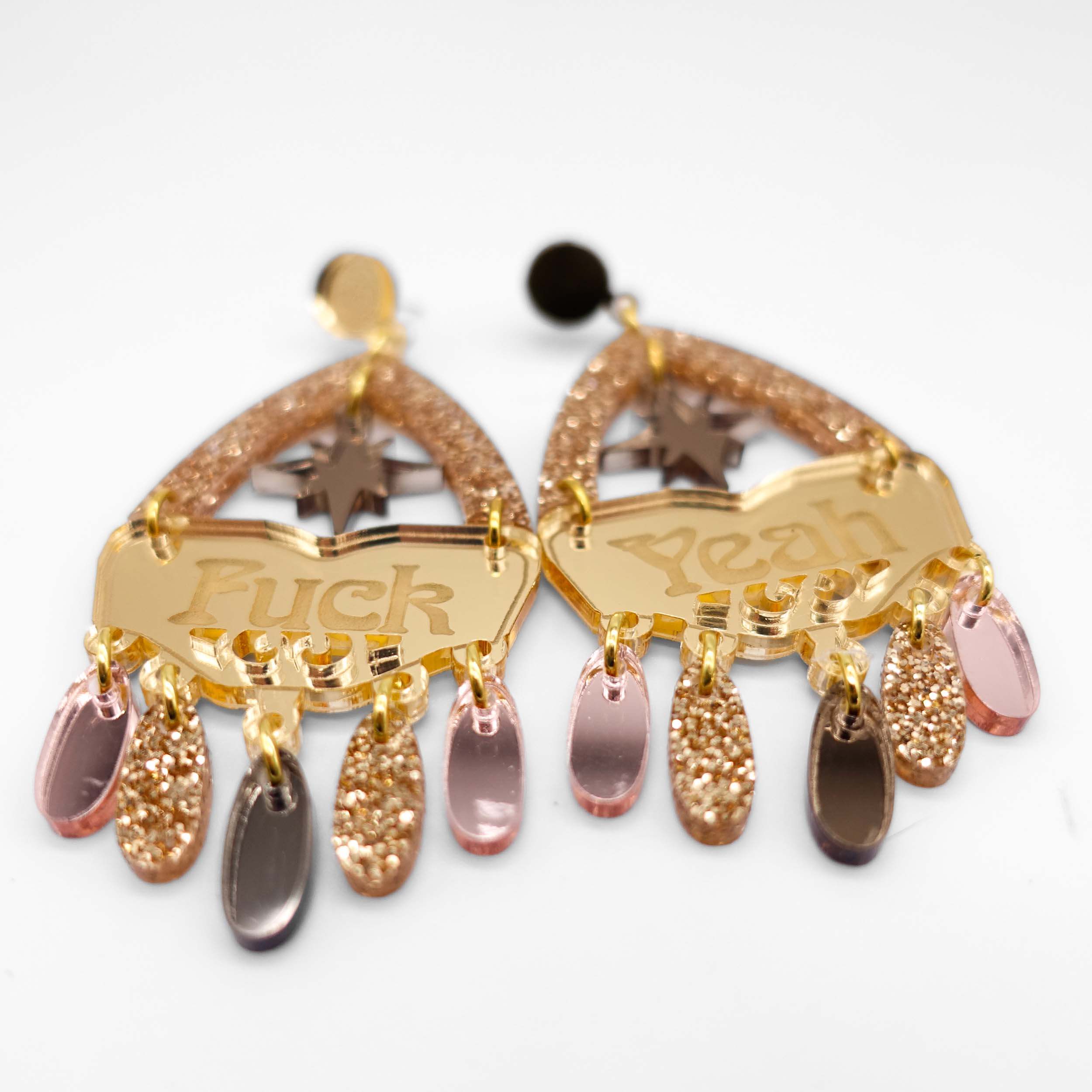 A close up of the F*ck Yeah statement earrings in golden colourway.