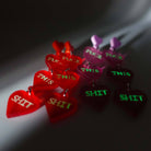 F*ck this Sh*t earrings in chilli red and pale pink, shown glowing in the dark.