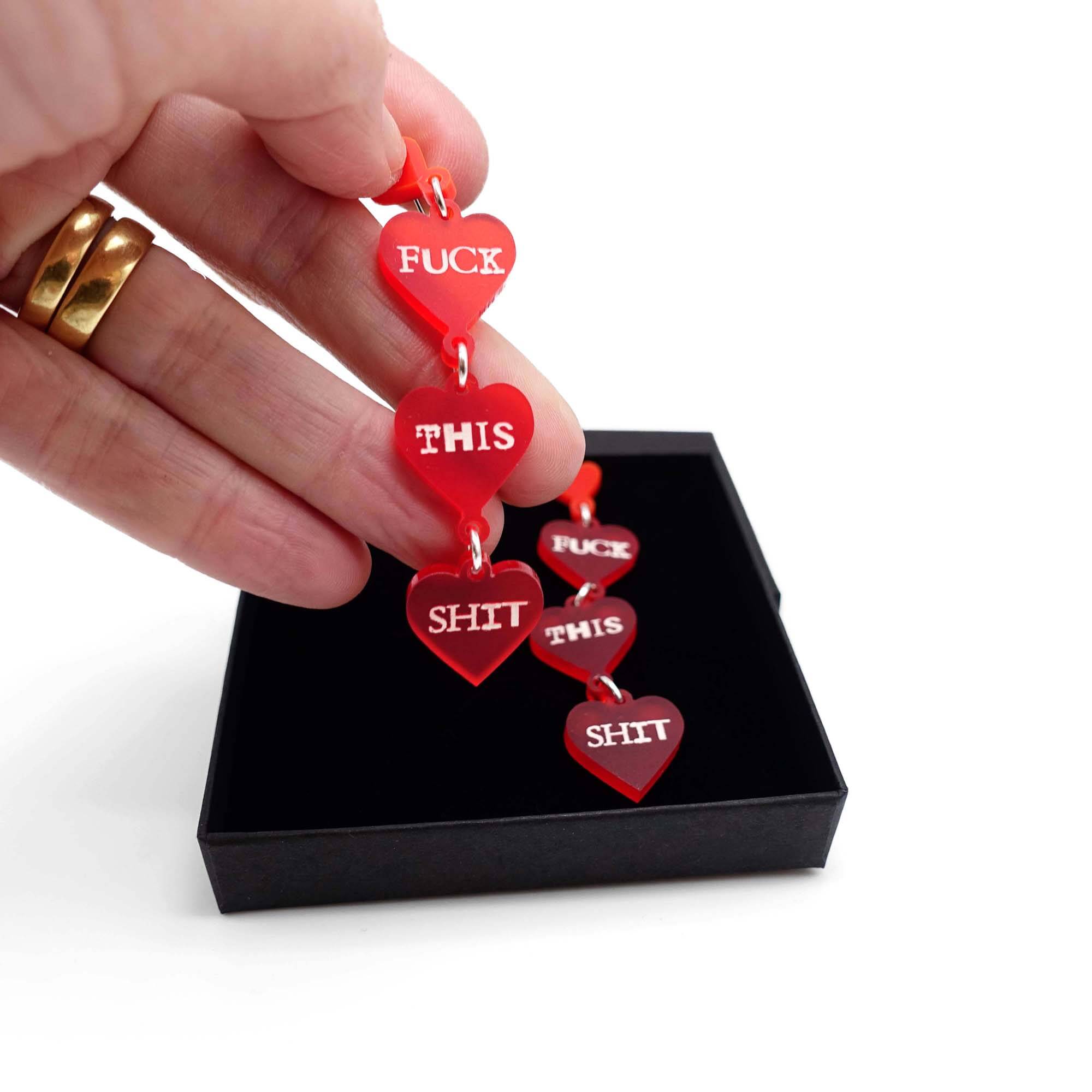 F*ck this Sh*t earrings in chilli red with glow-in-the-dark words being taken from a Wear and Resist gift box.