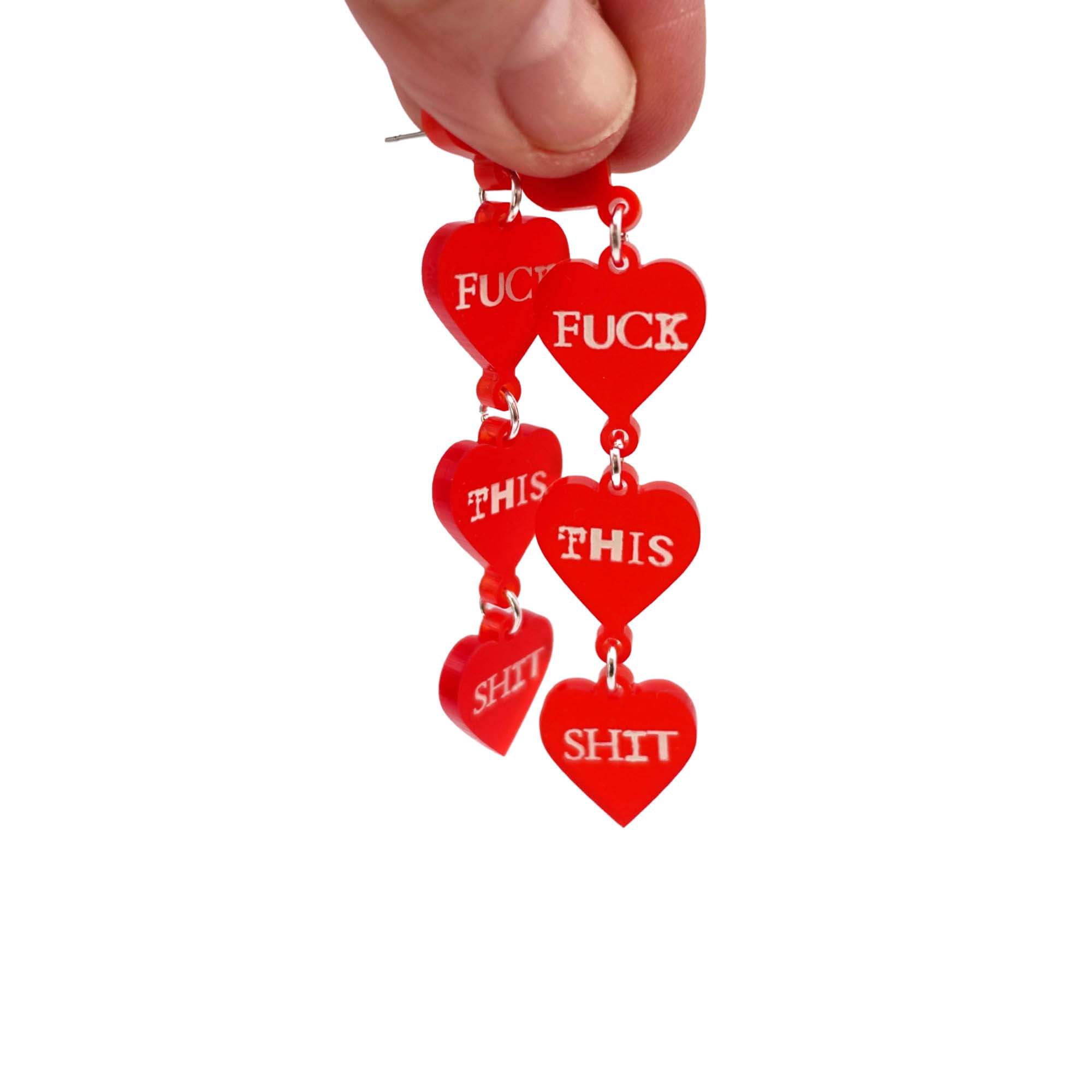 F*ck this Sh*t earrings in chilli red with glow-in-the-dark words, shown held up in my hand against a white background.