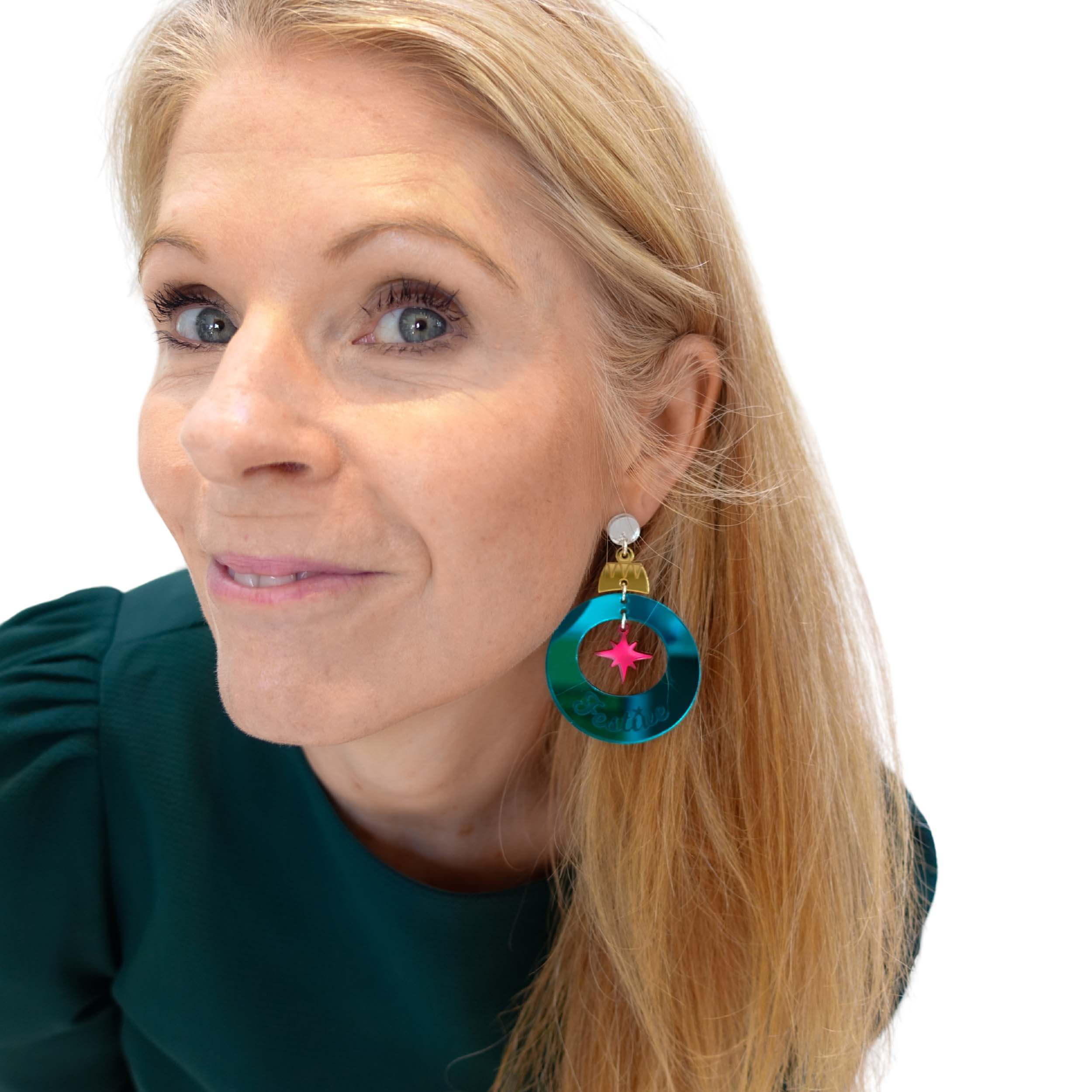 Sarah Day, founder of Wear and Resist wears the F*ckin Festive Christmas bauble earrings in ruby and teal mirror, focusing here on the teal Festive bauble.