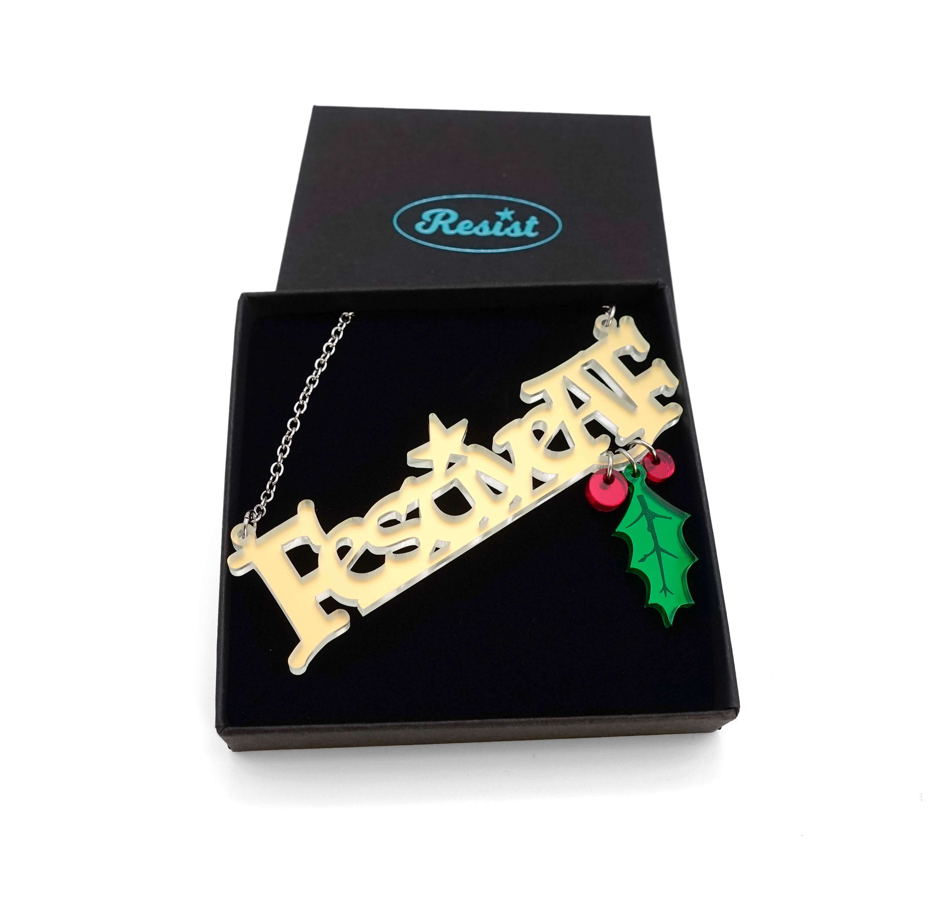 Festive AF matte iridescent necklace with hanging holly leaf and berries, shown in a Wear and Resist gift box.