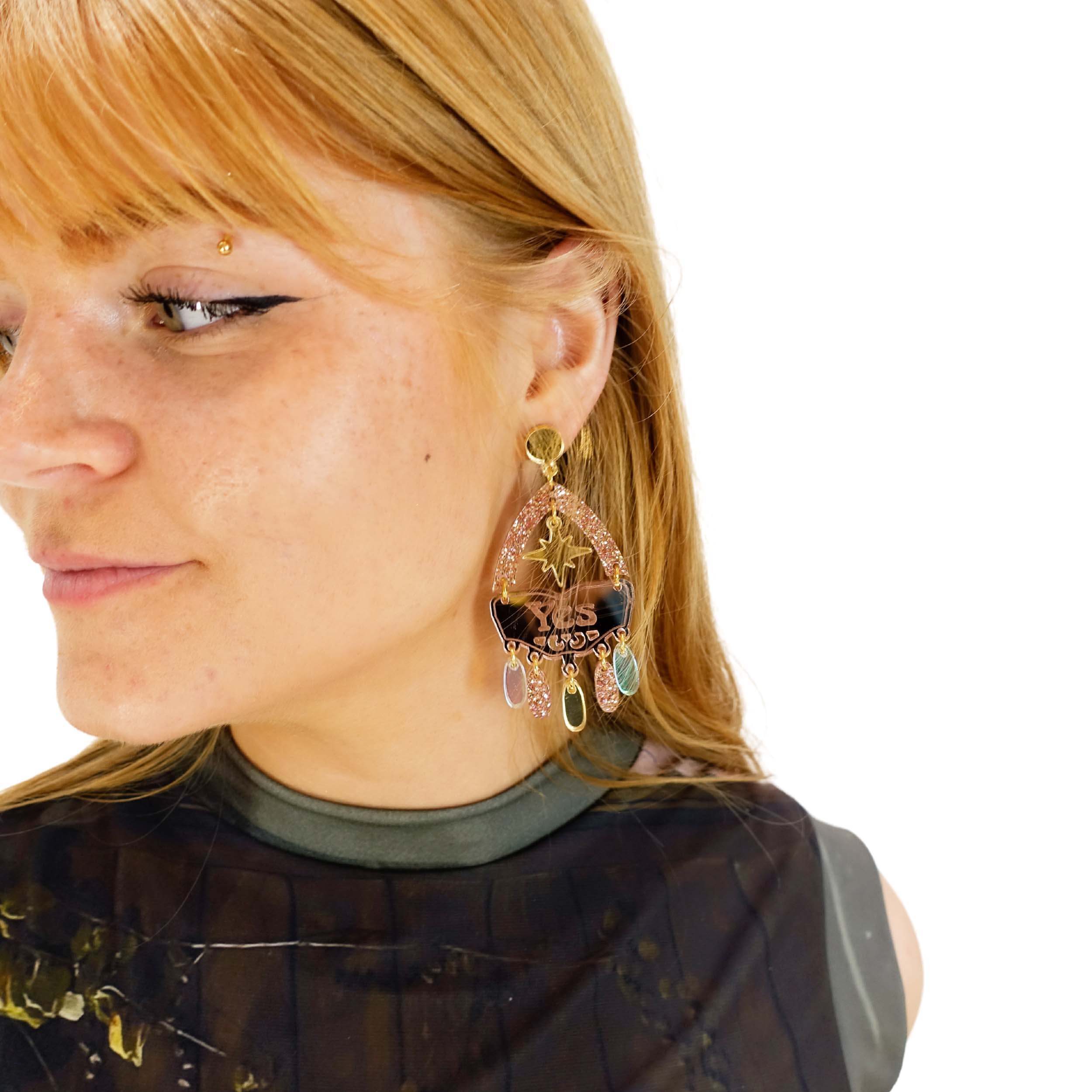 A close up of Eliza wearing Western style Hell Yes statement earrings in rose gold.