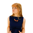 Eliza wears a Hell Yes necklace in day-glo orange.