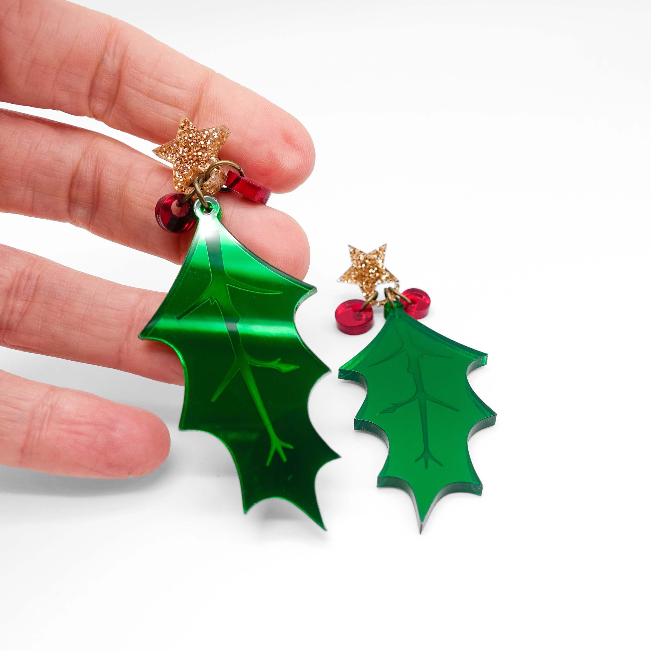 Statement Holly earrings with berries and gold glitter star tops, shown being held up for scale against a white background.