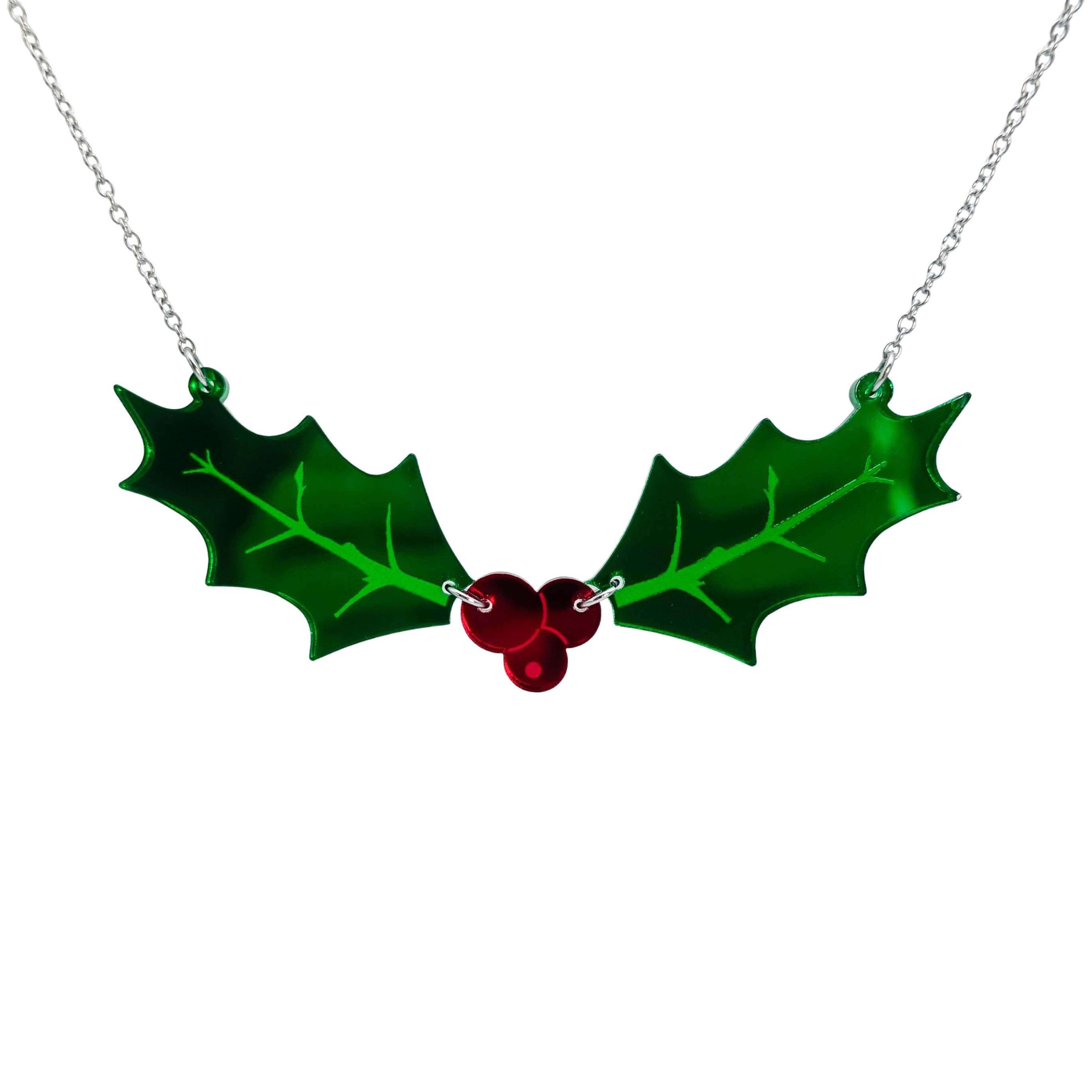 Naturalist Holly necklace with two holly leavs joined by a trio of red berries in mirror acrylic, shown hanging on a stainless steel chain against a white background.
