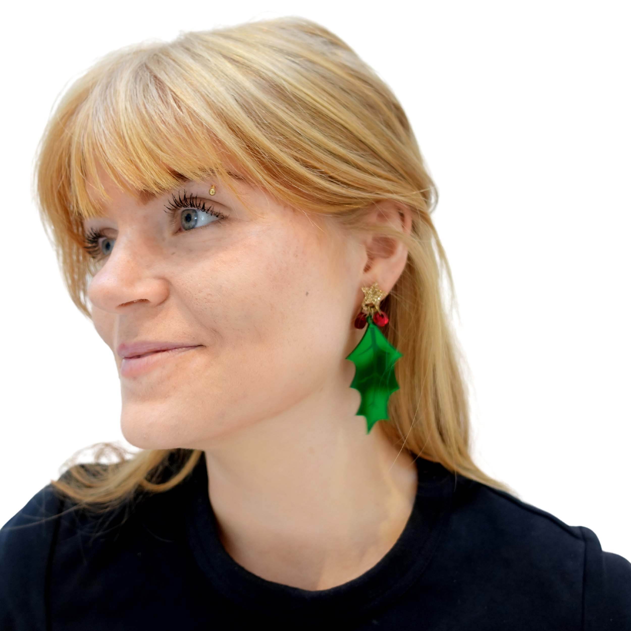 Eliza turning to the side wearing the Statement Holly earrings, designed by Sarah Day for the Wear and Resist Christmas Collection.