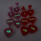 I Love Me heart drop earrings shown glowing in the dark.