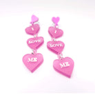 I Love Me heart drop earrings in pale pink frost with glow-in-the-dark etched words, shown on a white background.Self love is the best love!