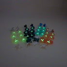 A group shot of all of the  I am I am I am heart drop earrings glowing in the dark.