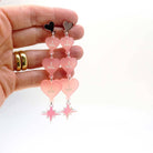 Blush frost  I am I am I am heart drop earrings shown held up for scale.