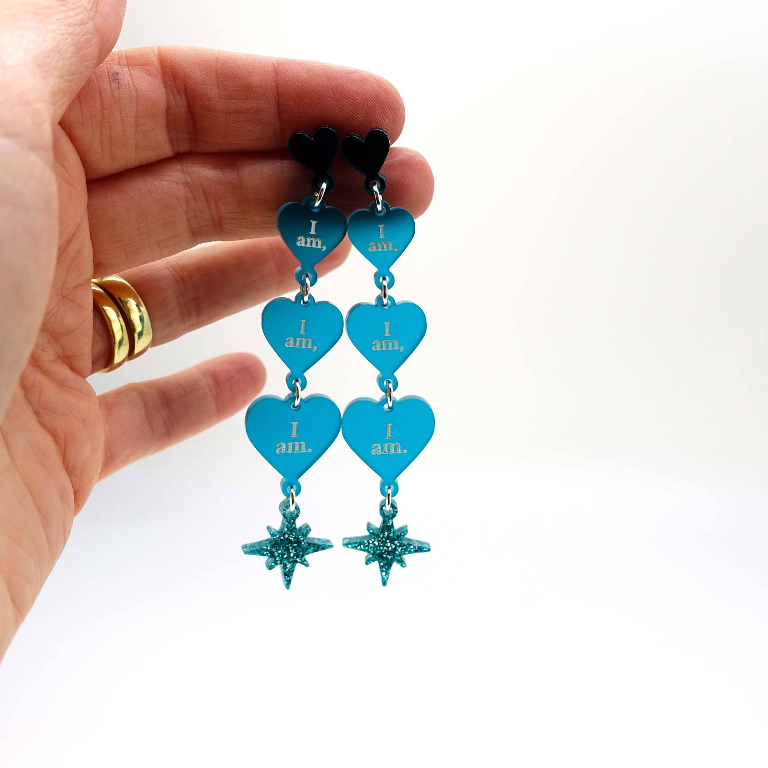 Teal frost  I am I am I am heart drop earrings shown held up for scale. 