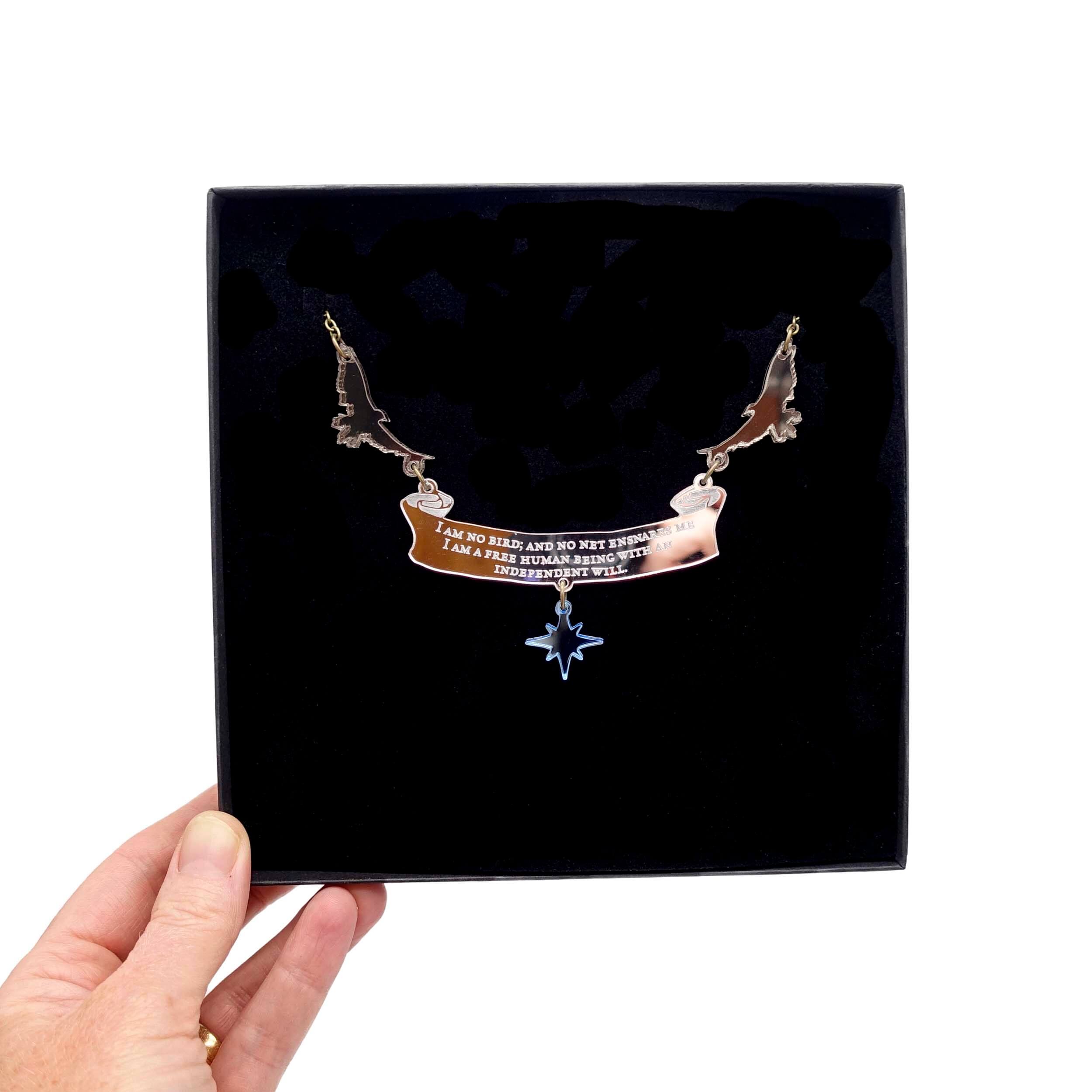 'I am no bird' statement Jane Eyre, Charlotte Brontë necklace shown held up in a large Wear and Resist gift box. Designed by Sarah Day of Wear and Resist in collaboration with the Brontë Parsonage Museum.  £2 from the sale of every piece in this collection will go to help support their Learning fund.