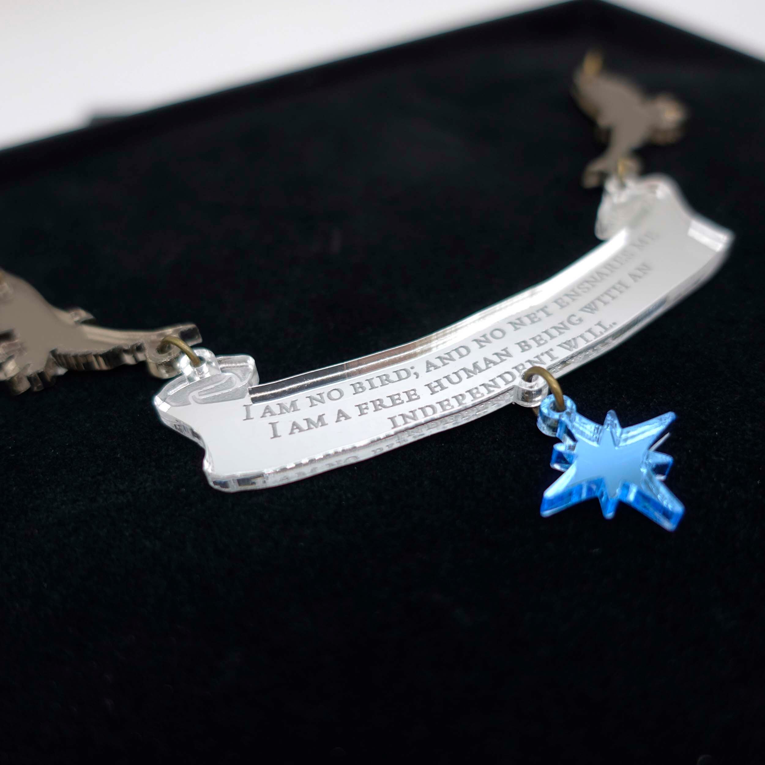 Close up of 'I am no bird' statement Jane Eyre, Charlotte Brontë necklace. Designed by Sarah Day of Wear and Resist in collaboration with the Brontë Parsonage Museum. £2 from the sale of every piece in this collection will go to help support their Learning fund.