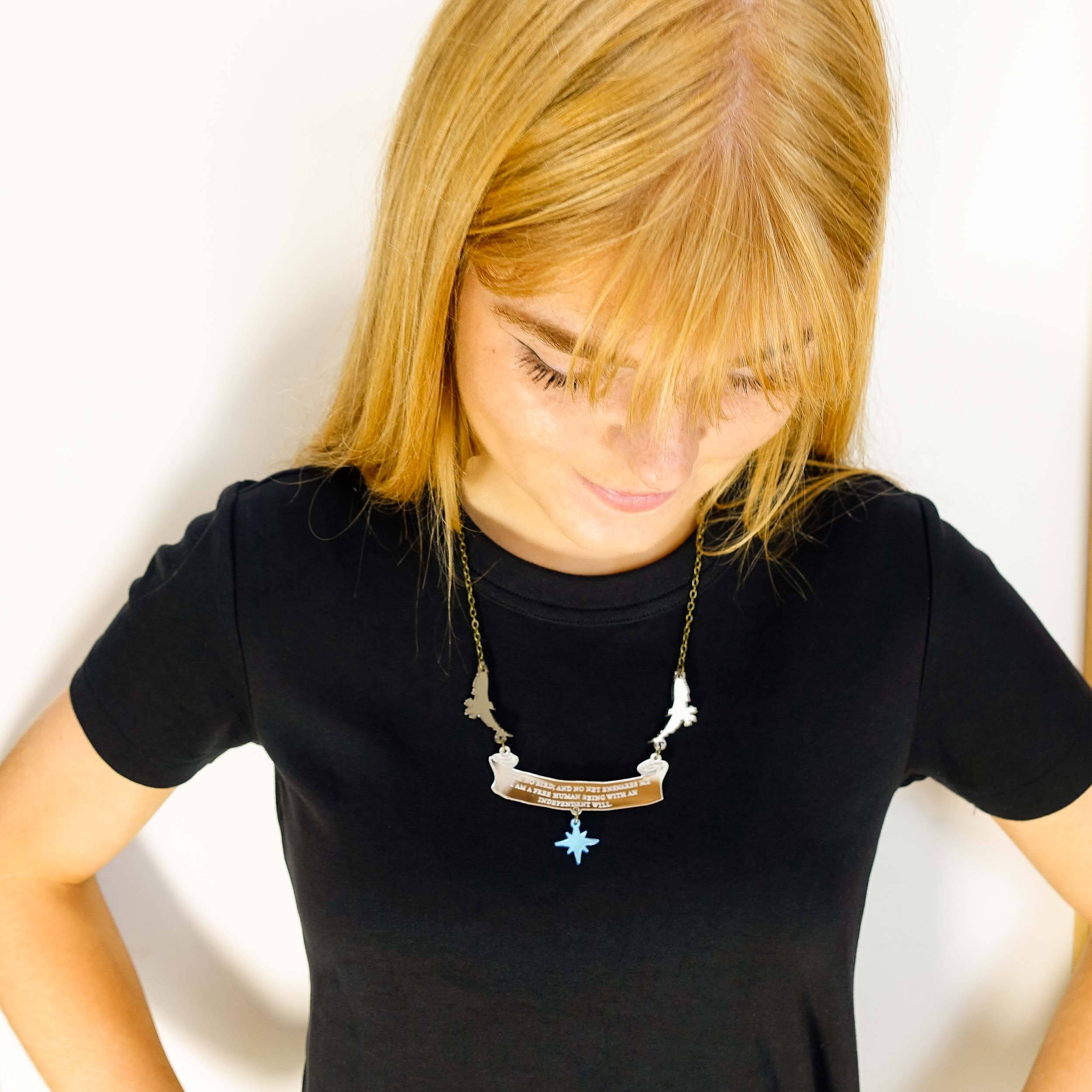 Eliza wears the 'I am no bird' Jane Eyre necklace with the words from Charlotte Brontë: 'I am no bird and no net ensares me, I am a free human being with an independent will,' etched on them. The necklace is held by two birds and finished with a star. Designed in collaboration with the the Brontë Parsonage Museum.