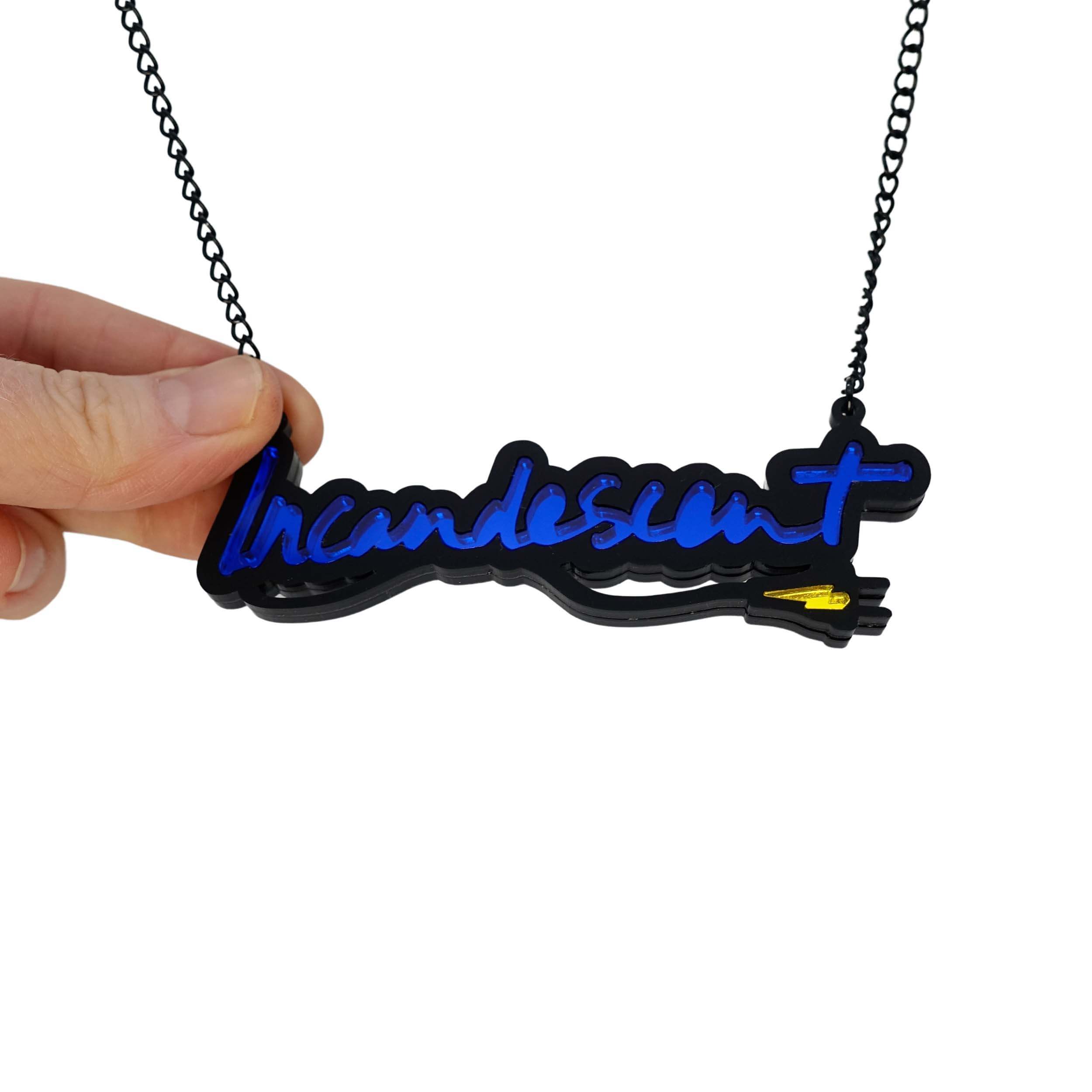 Incandescent neon necklace in electric blue with a yellow lightning bolt plug, on a black chain adjustable to three lengths. Shown hanging against a white backround with my hand holding it for scale.