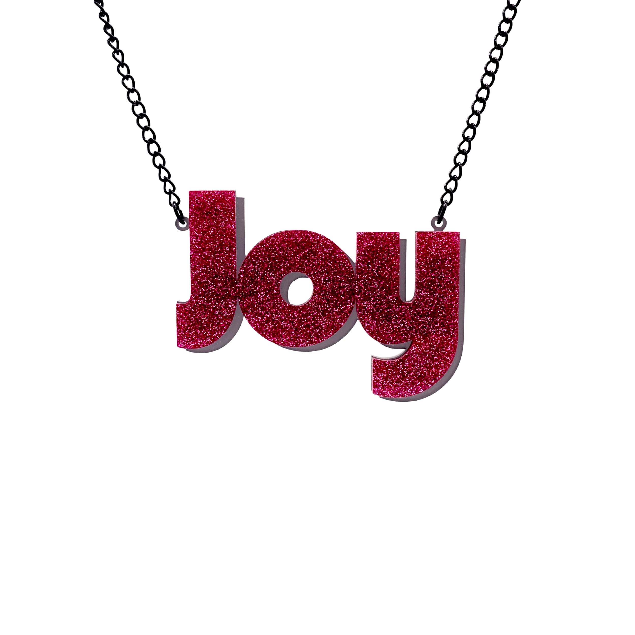 Joy statement necklace in hot pink glitter, with slate frost drop shadow backing layer. Shown hanging against a white background.