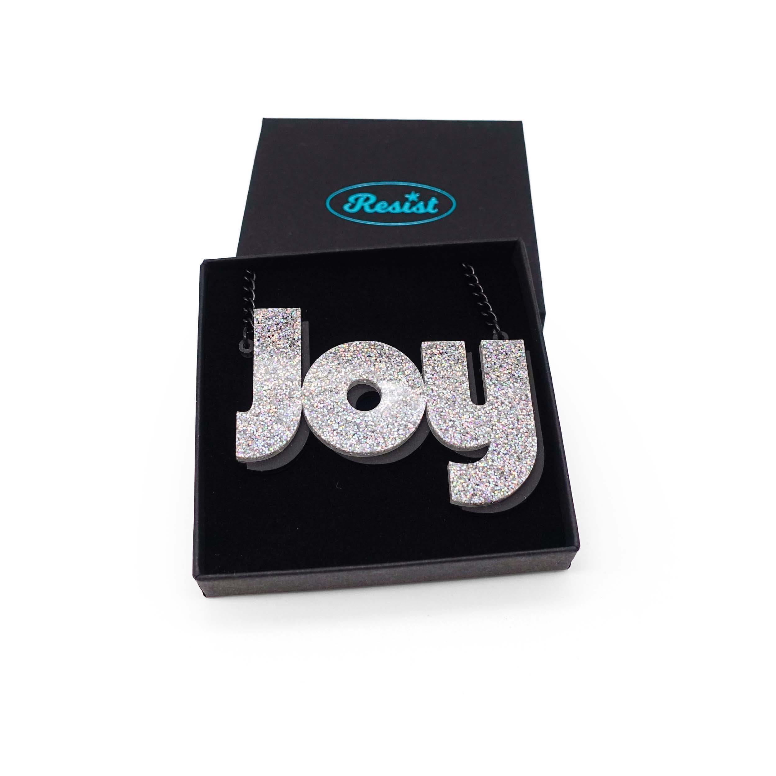 Joy statement necklace in silver glitter, shown in a Wear and Resist gift box.