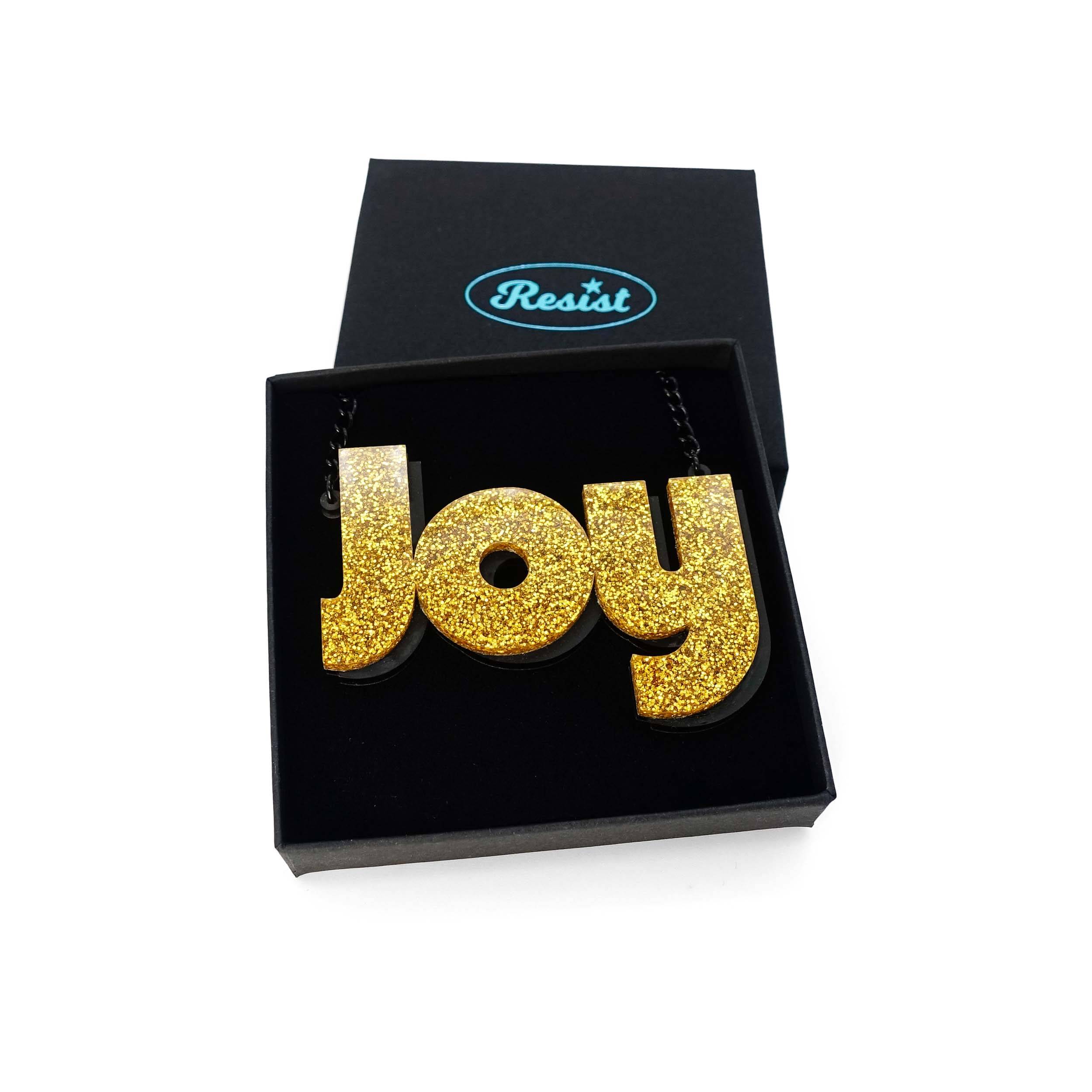 Joy statement necklace in ultra gold glitter, shown in a Wear and Resist gift box.