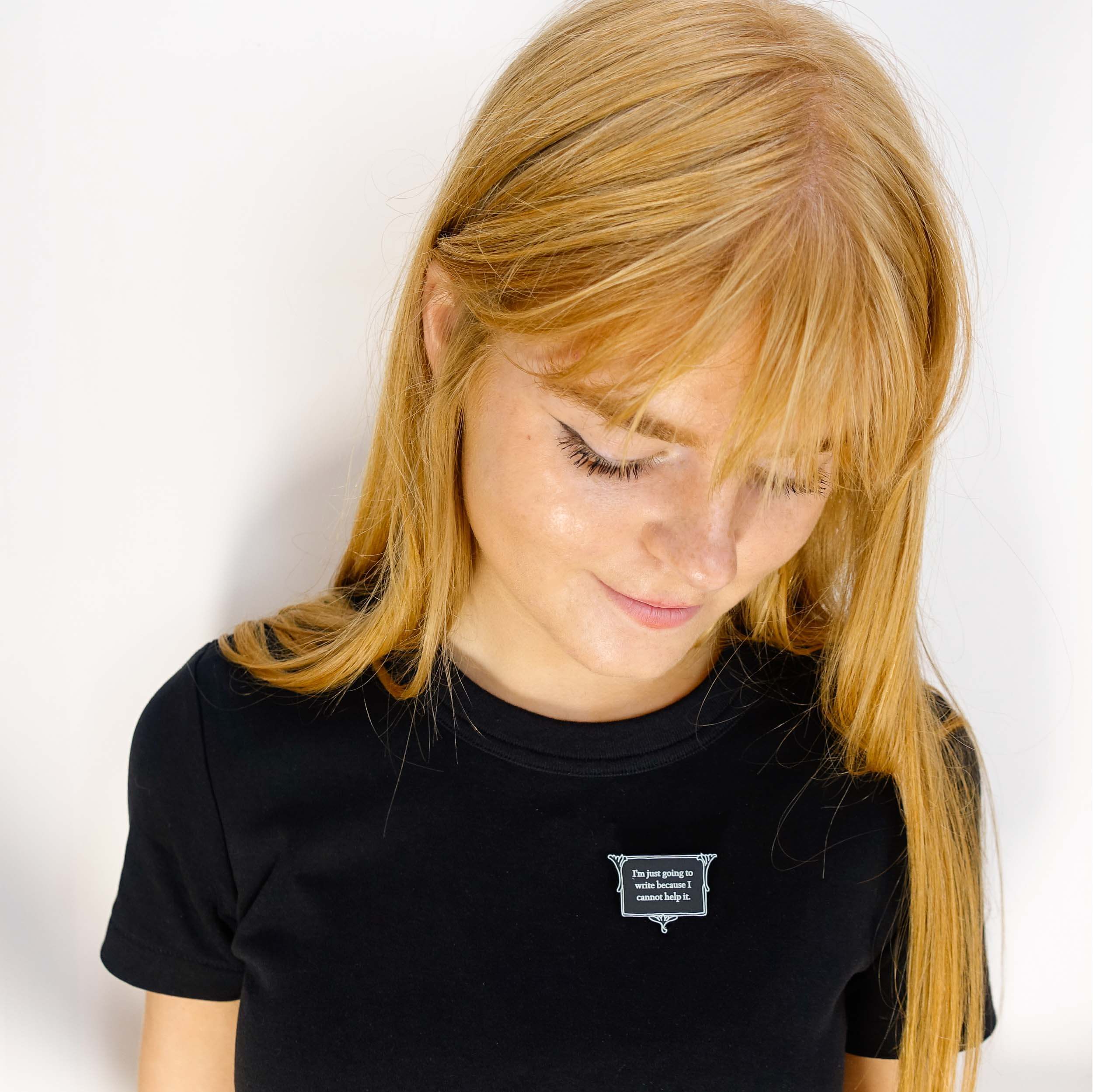 Eliza wears a vintage style black and white brooch etched in glow-in-the-dark pigment with Charlotte Bronte's words: 'I'm just going to write because I cannot help it.'
