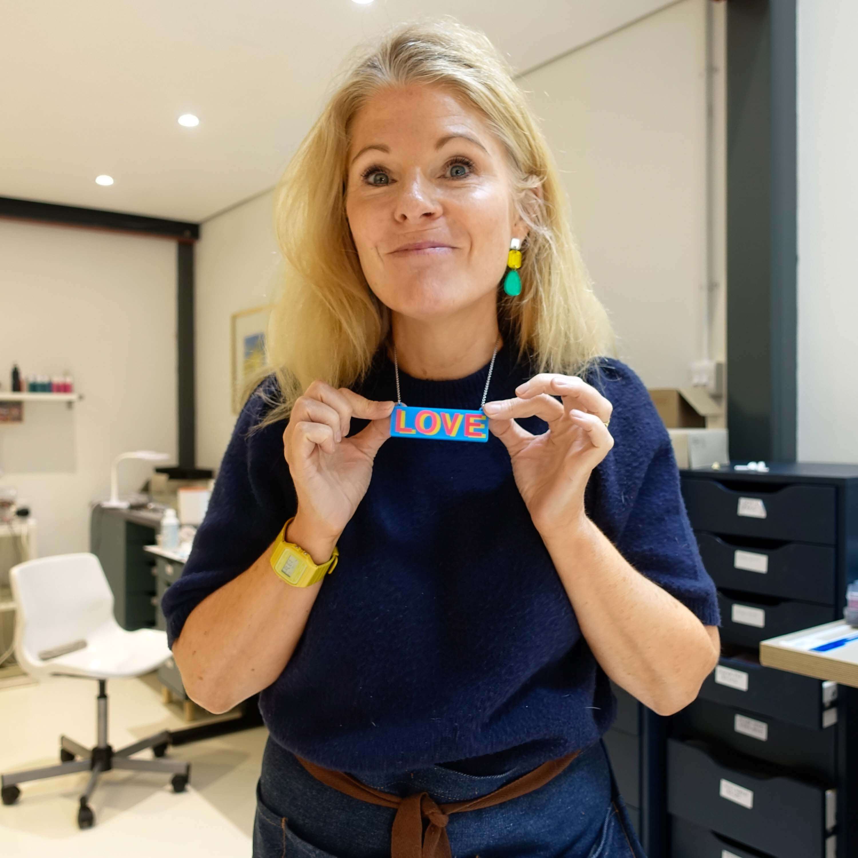 Sarah Day, founder of Wear and Resist, wears the LOVE necklace in her studio.