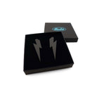 Large Lightning Bolt earrings in matte black, shown in a Wear and Resist gift box.