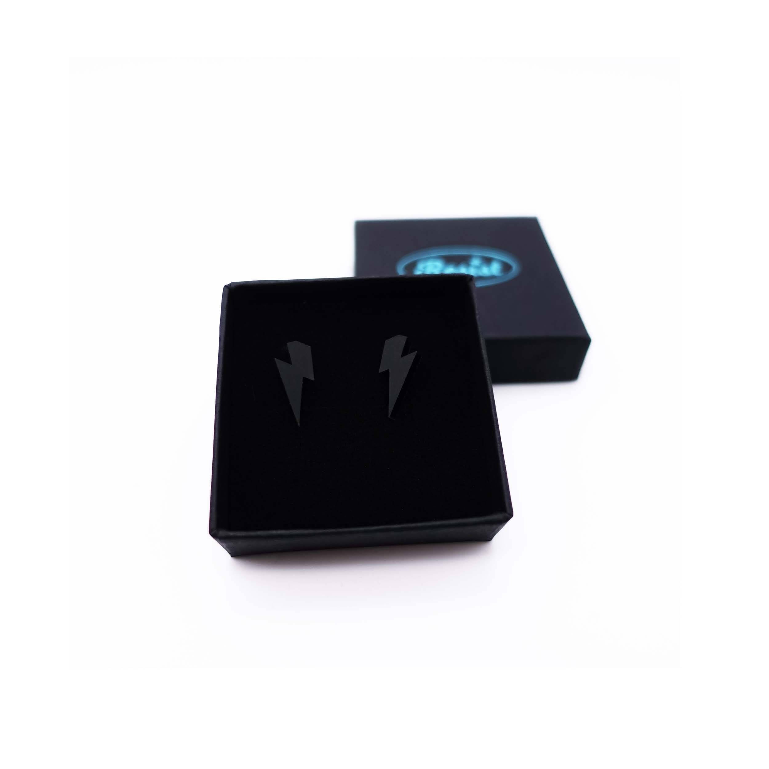 Tiny Lightning Bolt earrings in matte black, shown in a small Wear and Resist gift box.
