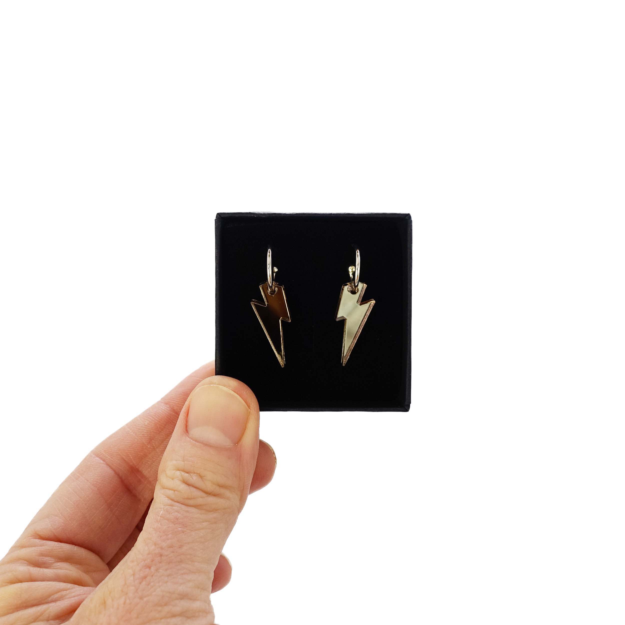 Small bronze mirror lightning bolt hoop earrings on silver plated hoops shown held up in a Wear and Resist gift box.