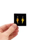 Small yellow lightning bolt hoop earrings shown held up in a small Wear and Resist gift box.