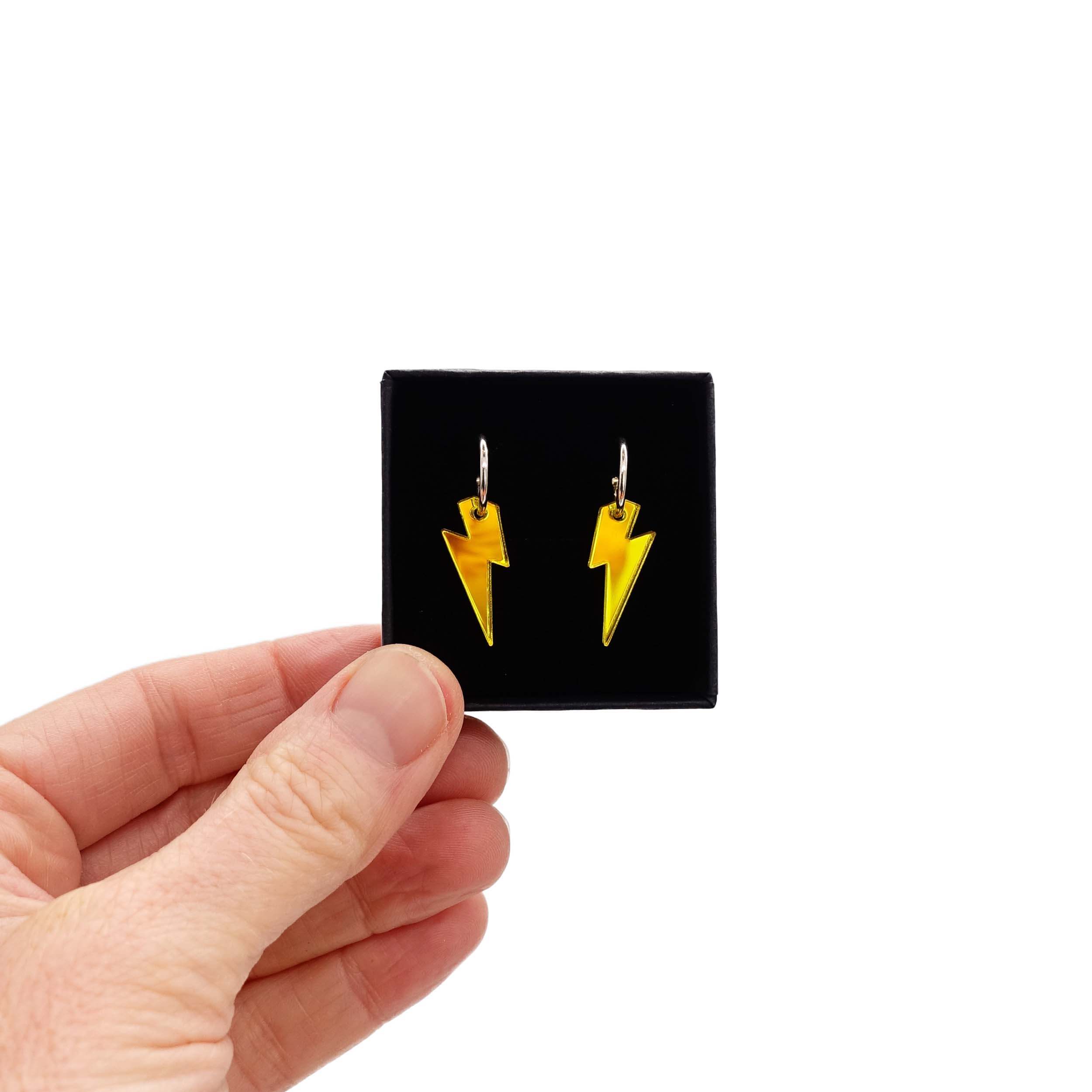 Small yellow lightning bolt hoop earrings shown held up in a small Wear and Resist gift box.