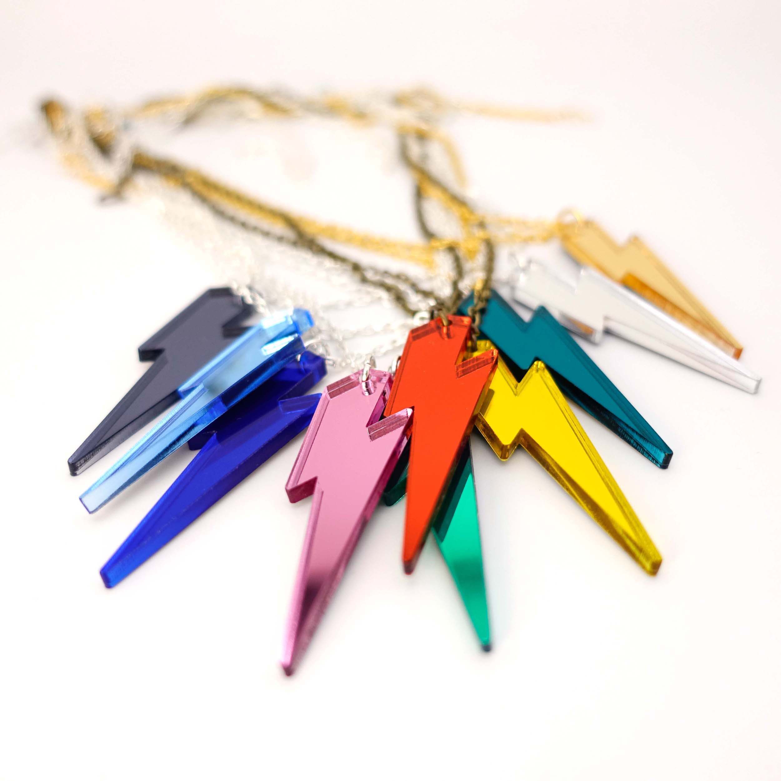 Lightning Bolt pendants shown in all ten mirror colours on a white surface.