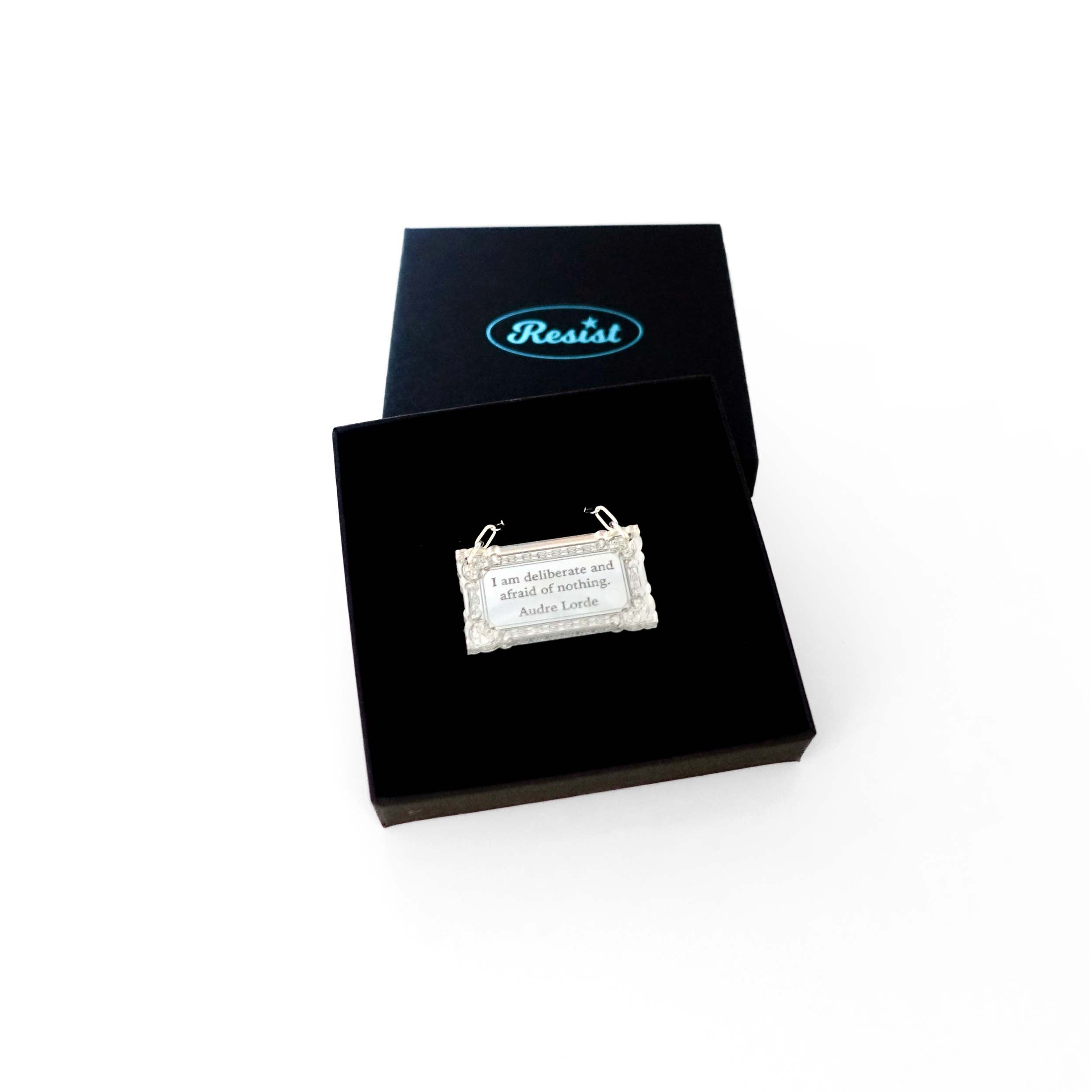 Literary Quote necklace etched with a quote by Audre Lorde, 'I am deliberate and afraid of nothing.' Shown in a Wear and Resist gift box.