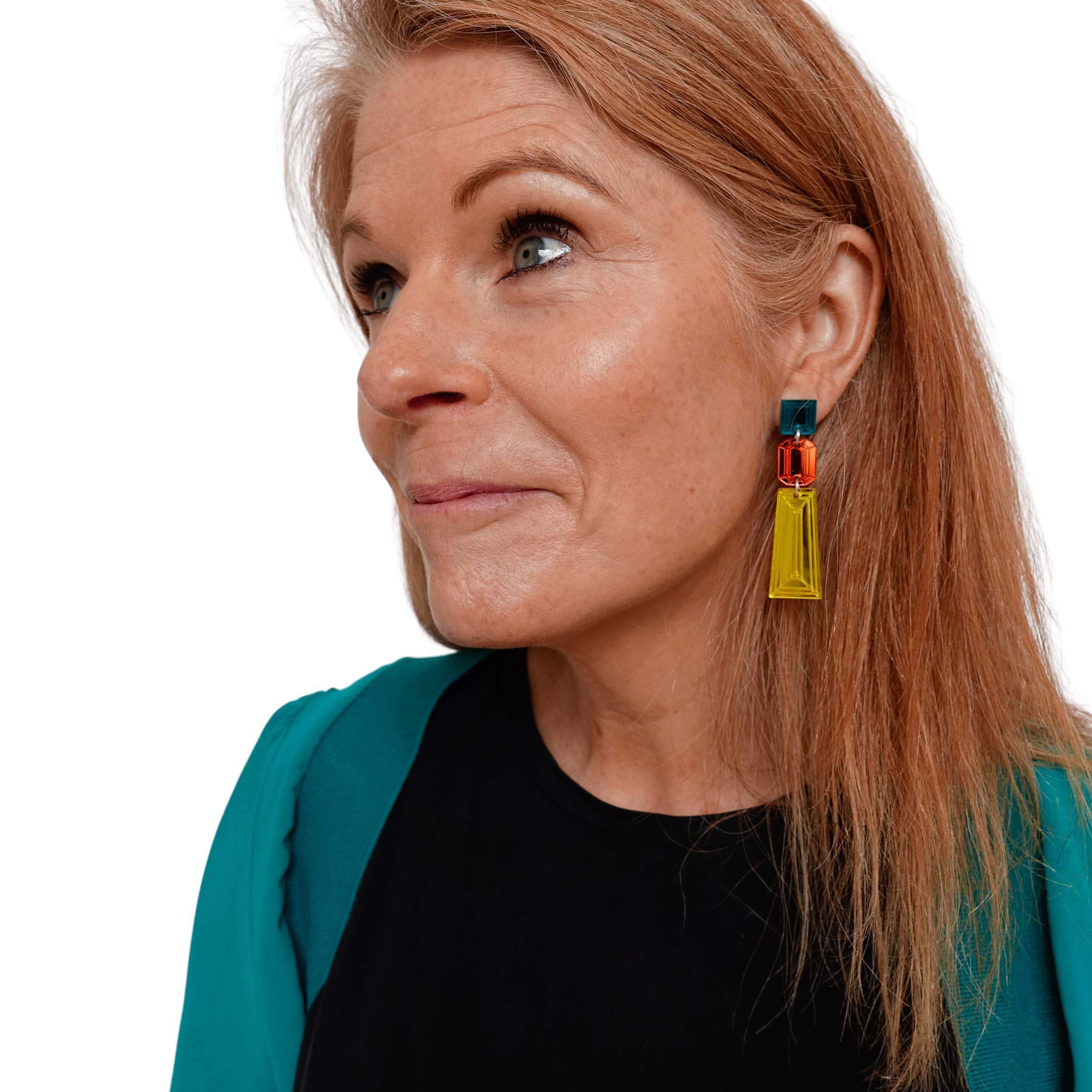 Sarah wears yellow, flame and teal long Deco Drop earrings. 