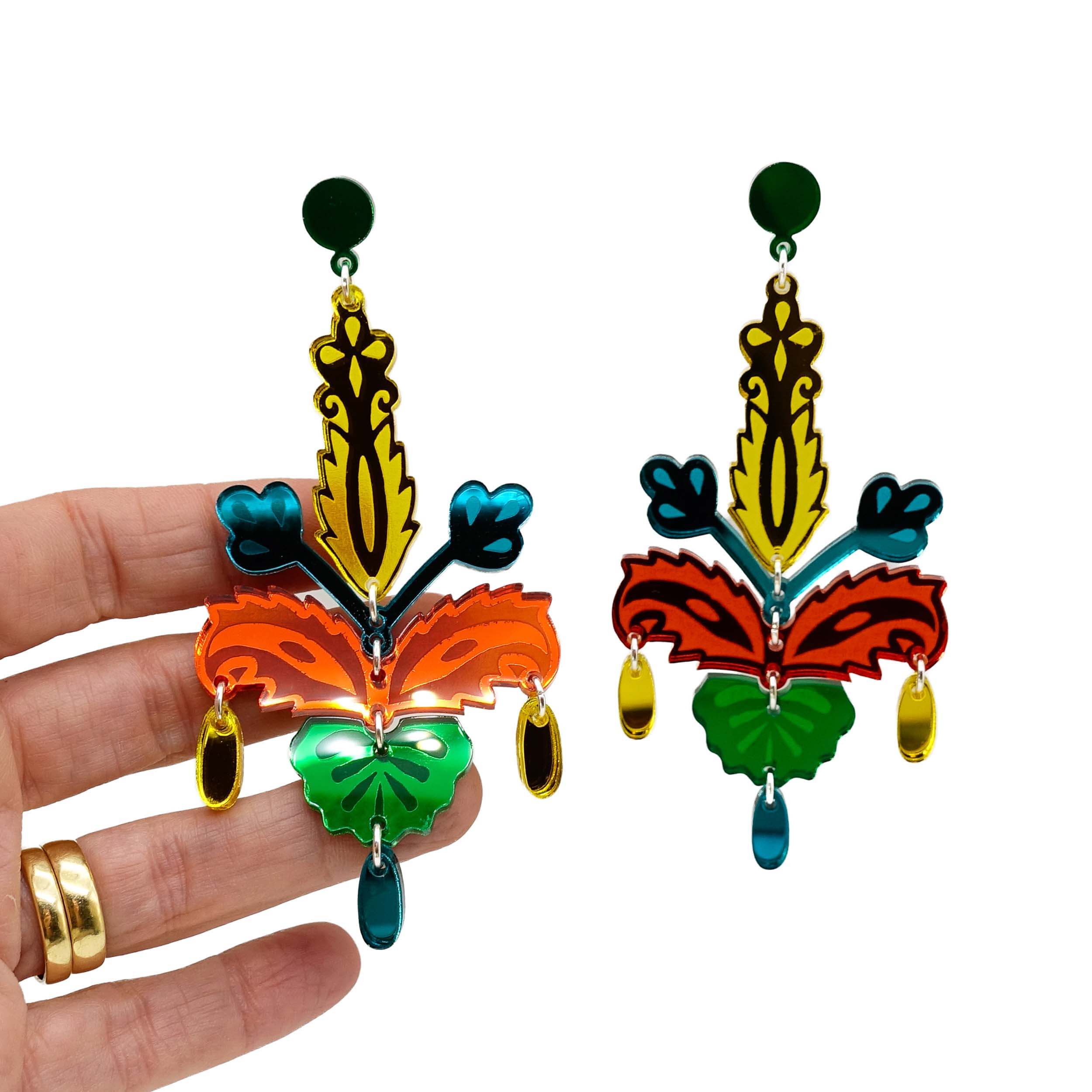 Mambo colourway Festive Drop statement earrings shown hanging against a white background with my hand behind for scale.
