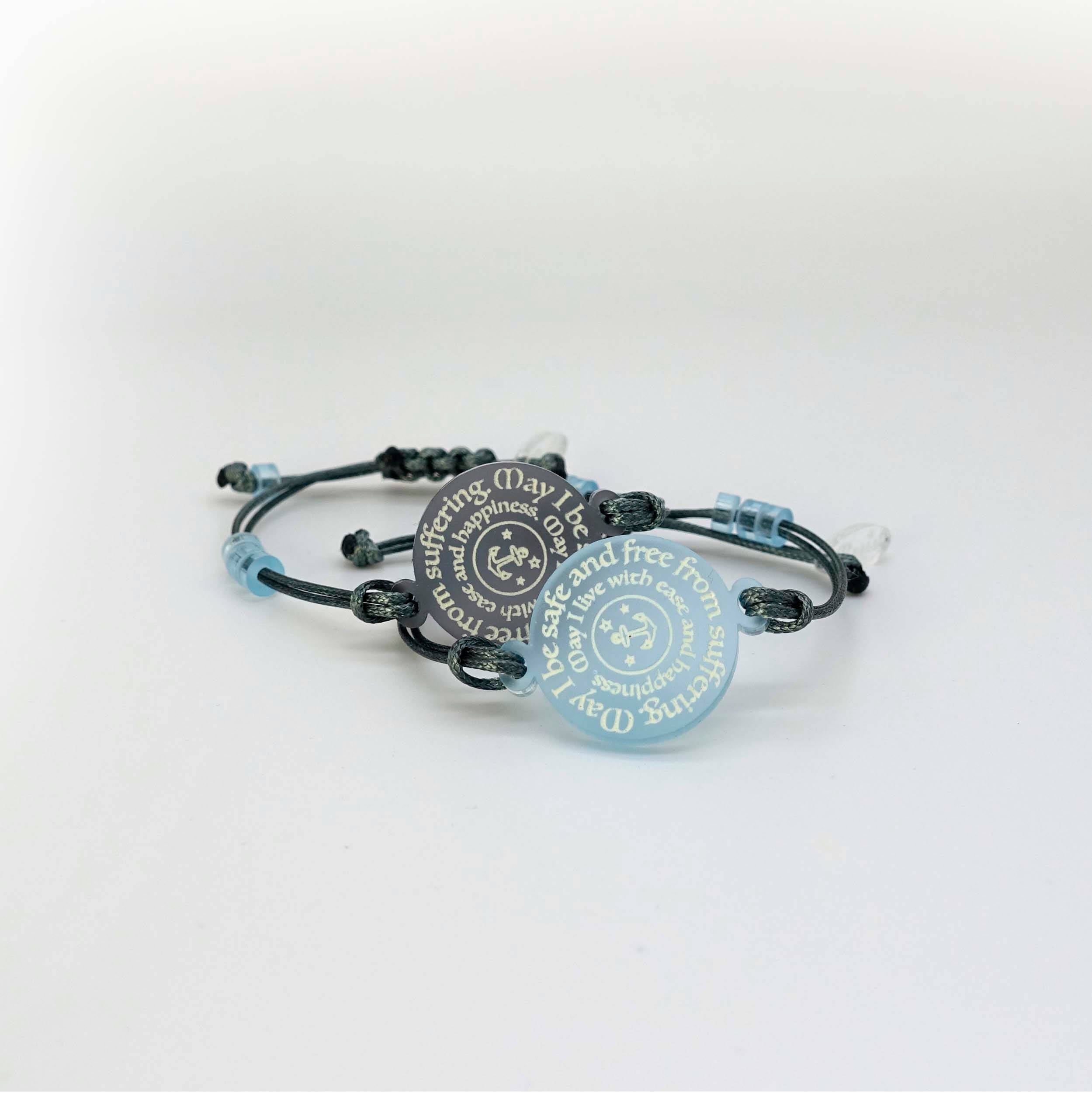 May I Be Safe bracelets in sea foam and shale shown against a white background.